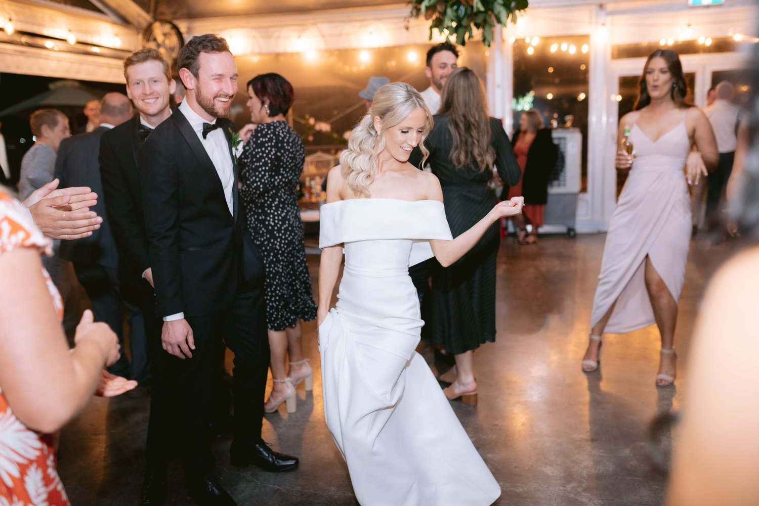 Bride dancing at a wedding reception with guests in formal attire.