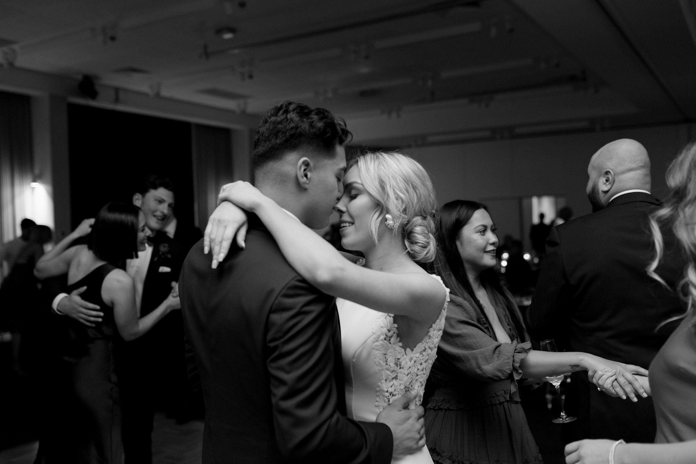 Couples dancing at a wedding reception, with a bride and groom embracing closely.