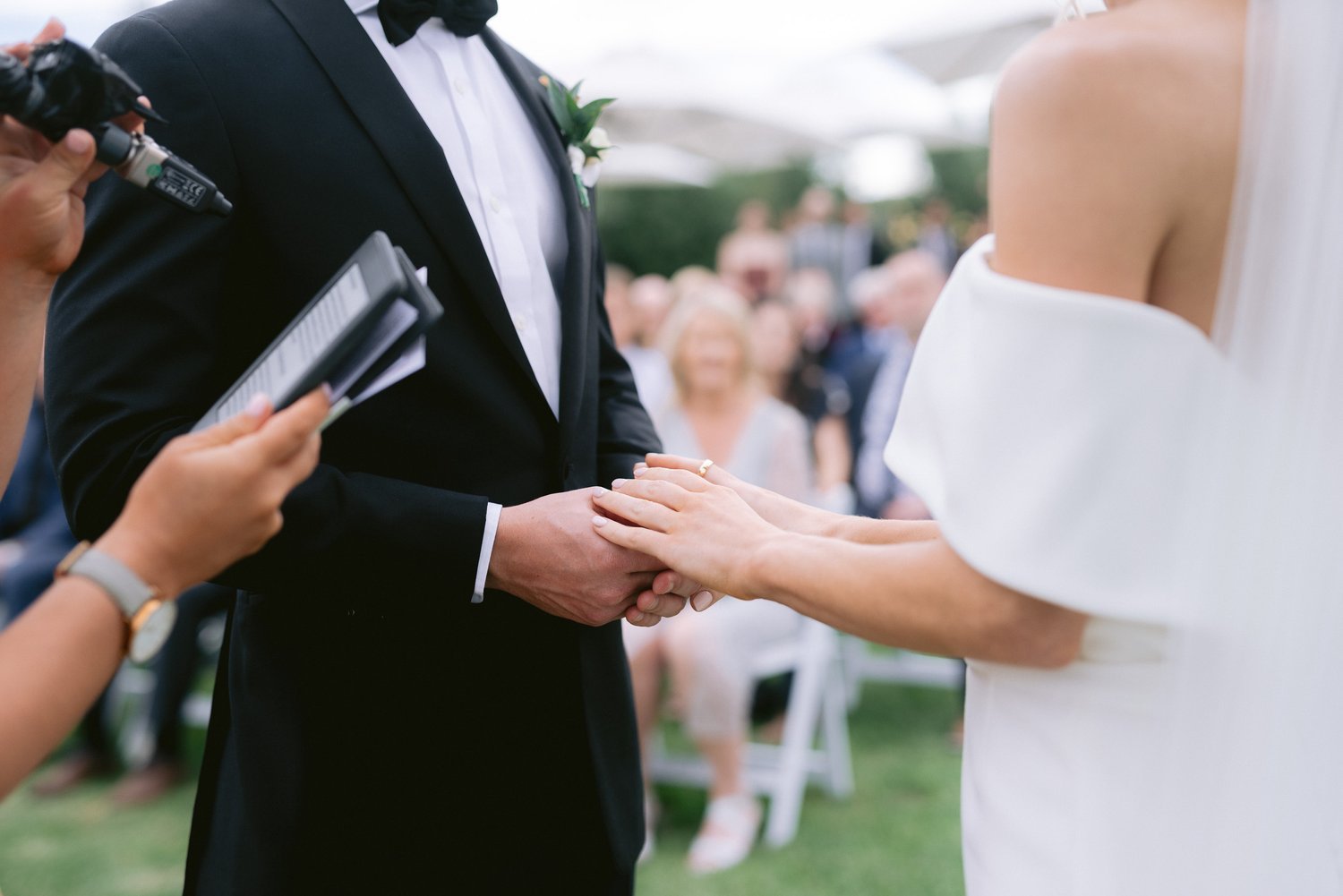 Bride and groom holding hands during outdoor wedding ceremony