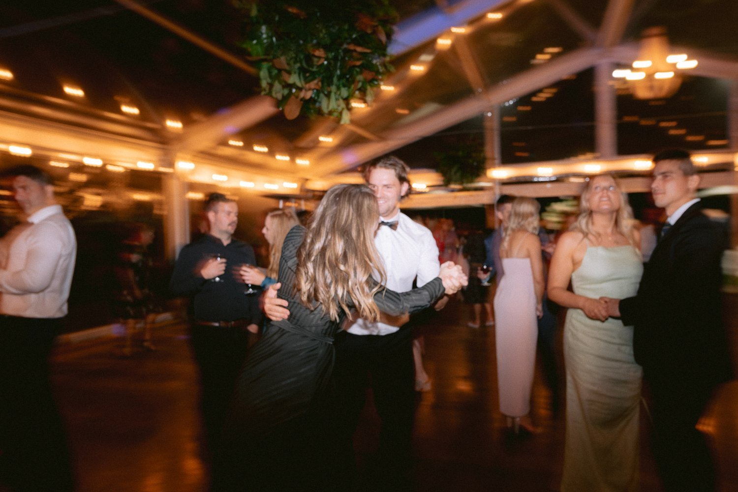 People dancing at an indoor event with blurred motion and warm lighting.