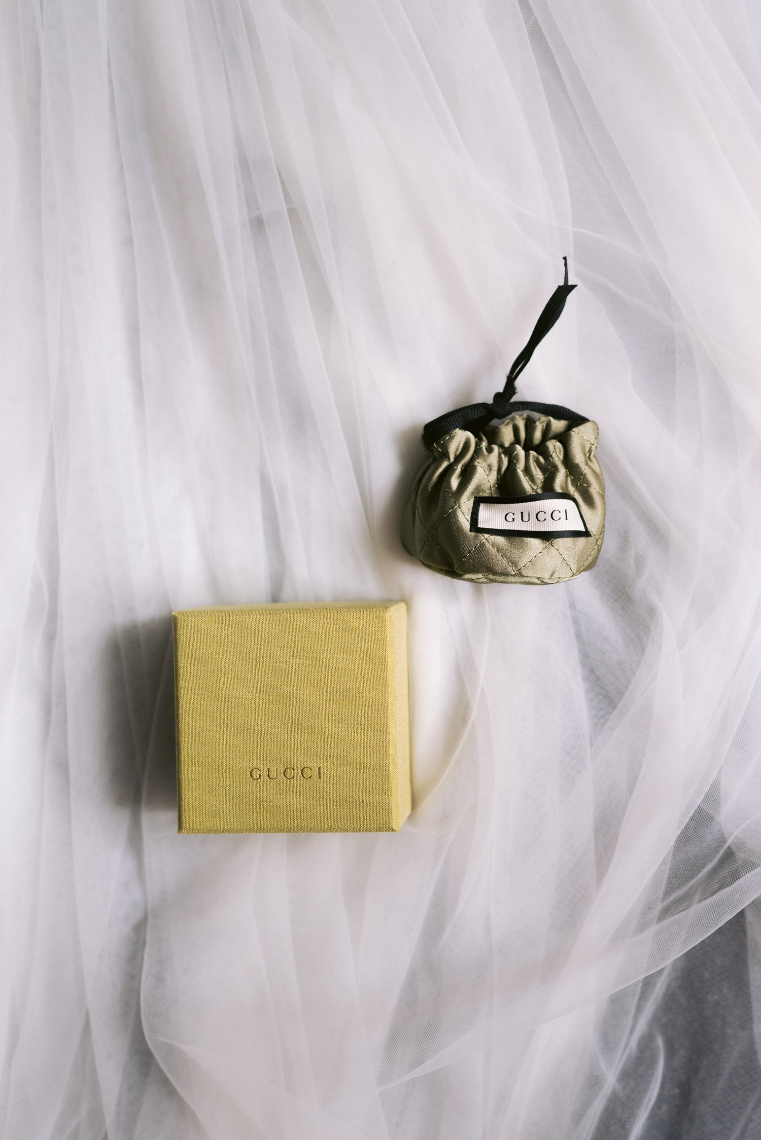 A Gucci box and small drawstring pouch on white fabric.