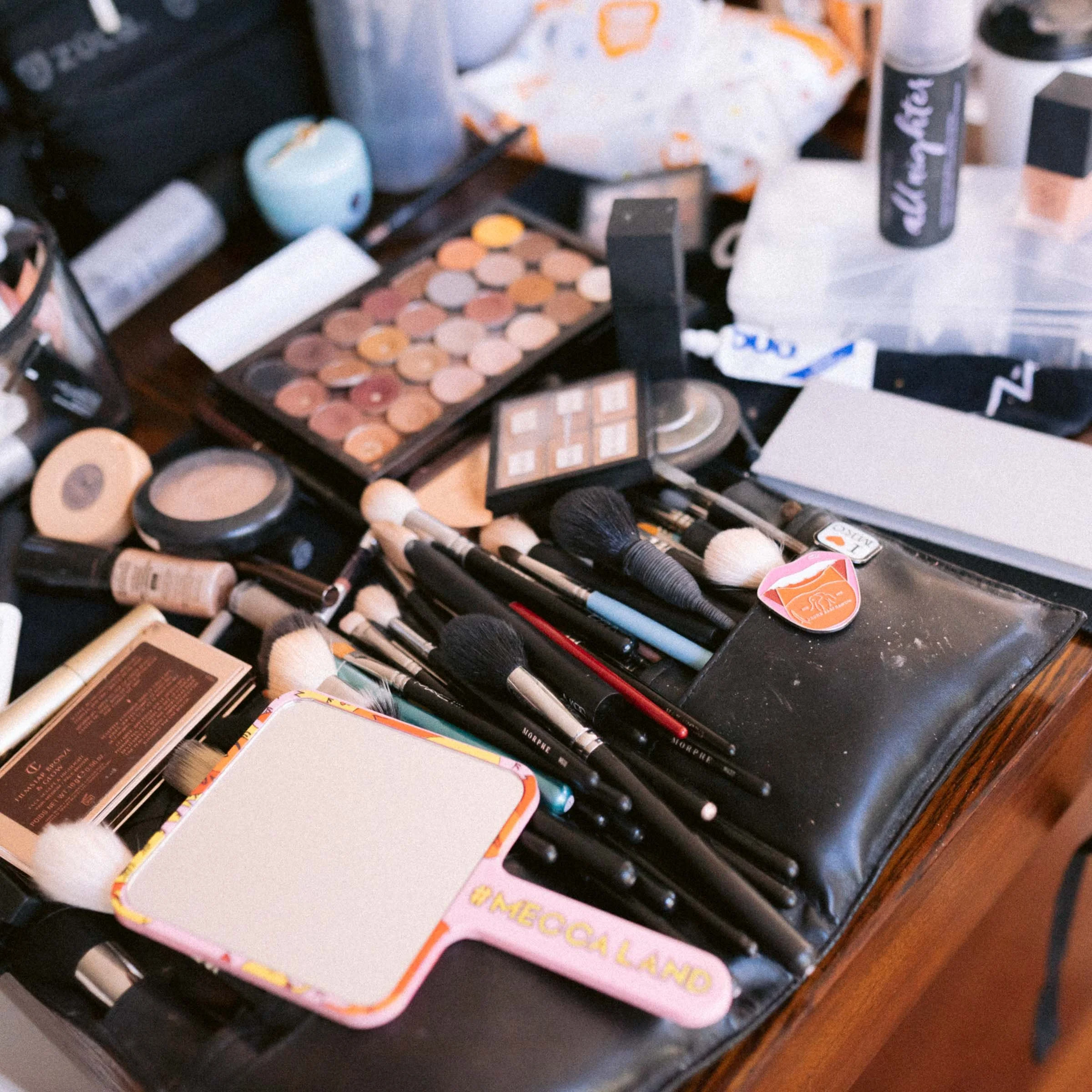 Collection of makeup brushes, palettes, and cosmetics on a table.