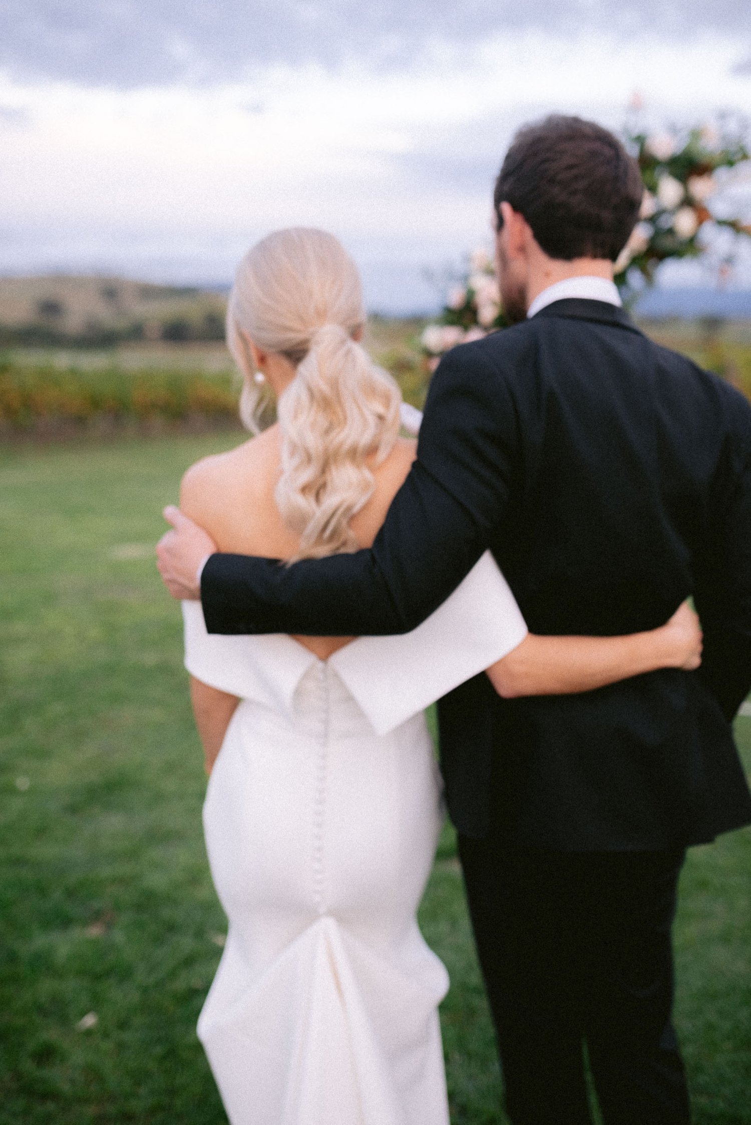 Bride and groom embracing in a field