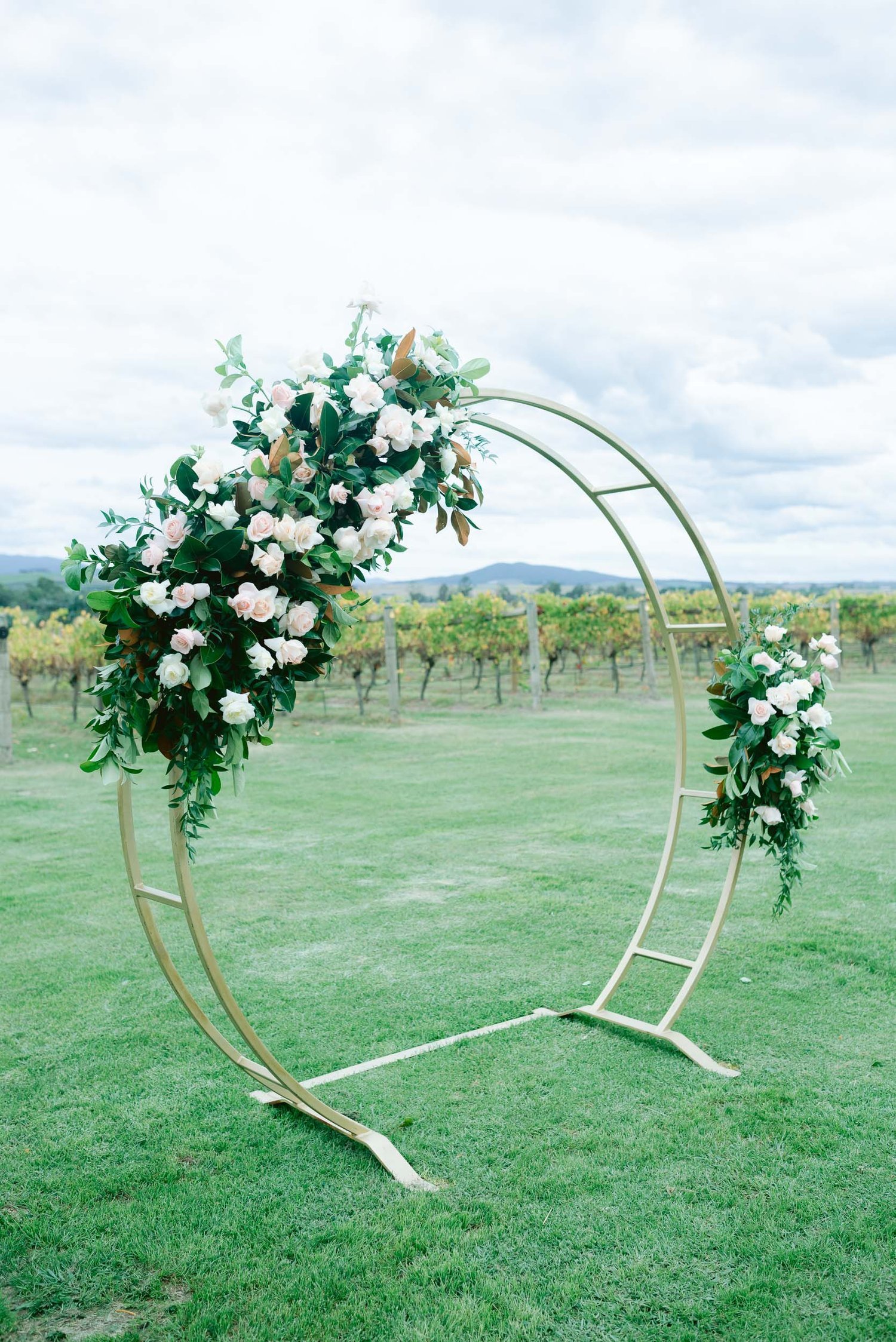 Circular wedding arch with flowers on grassy field