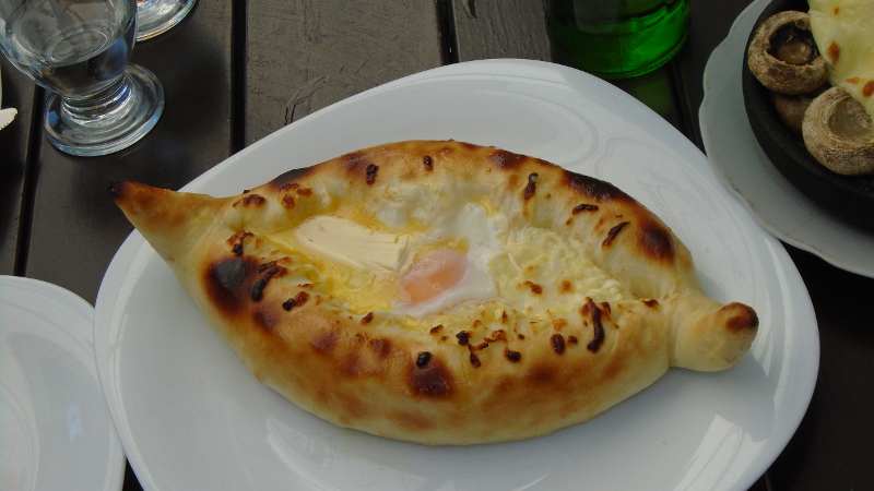 This is fancy ხათჩაპური. The dough is formed into a boat with hot cheese in the center. A raw egg and pat of butter floats on the cheese. To eat, you tear off pieces of bread and stir them in the center, mixing it all. You generally only see this in restaurants.