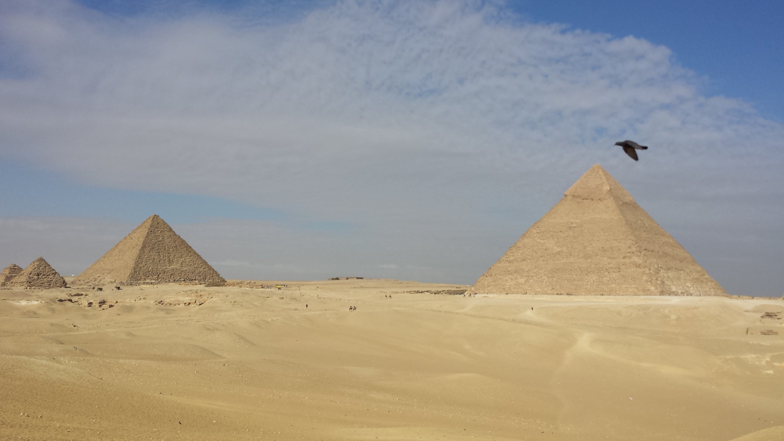 A falcon flies in front of Khafre's pyramid. Menkaure's pyramid and those of his queens are on the left.