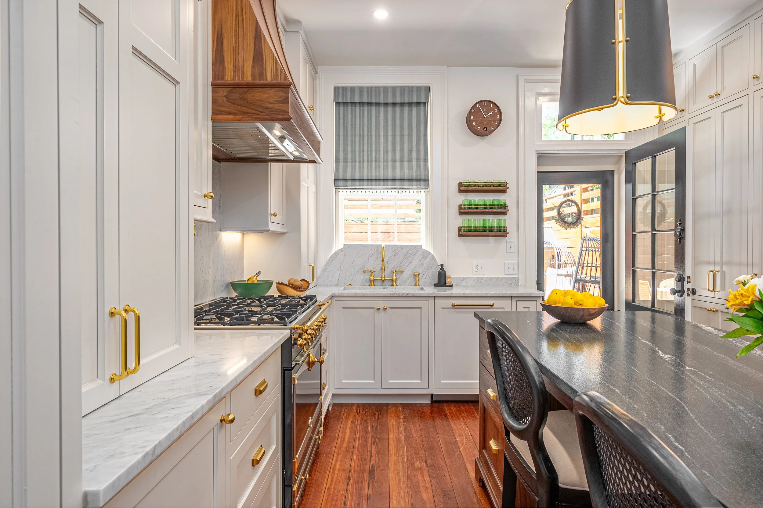   Custom Roman shade with pom trim, which adds the perfect finishing touch in the kitchen of this renovated historic townhouse. Photography by Voyage Creative.  