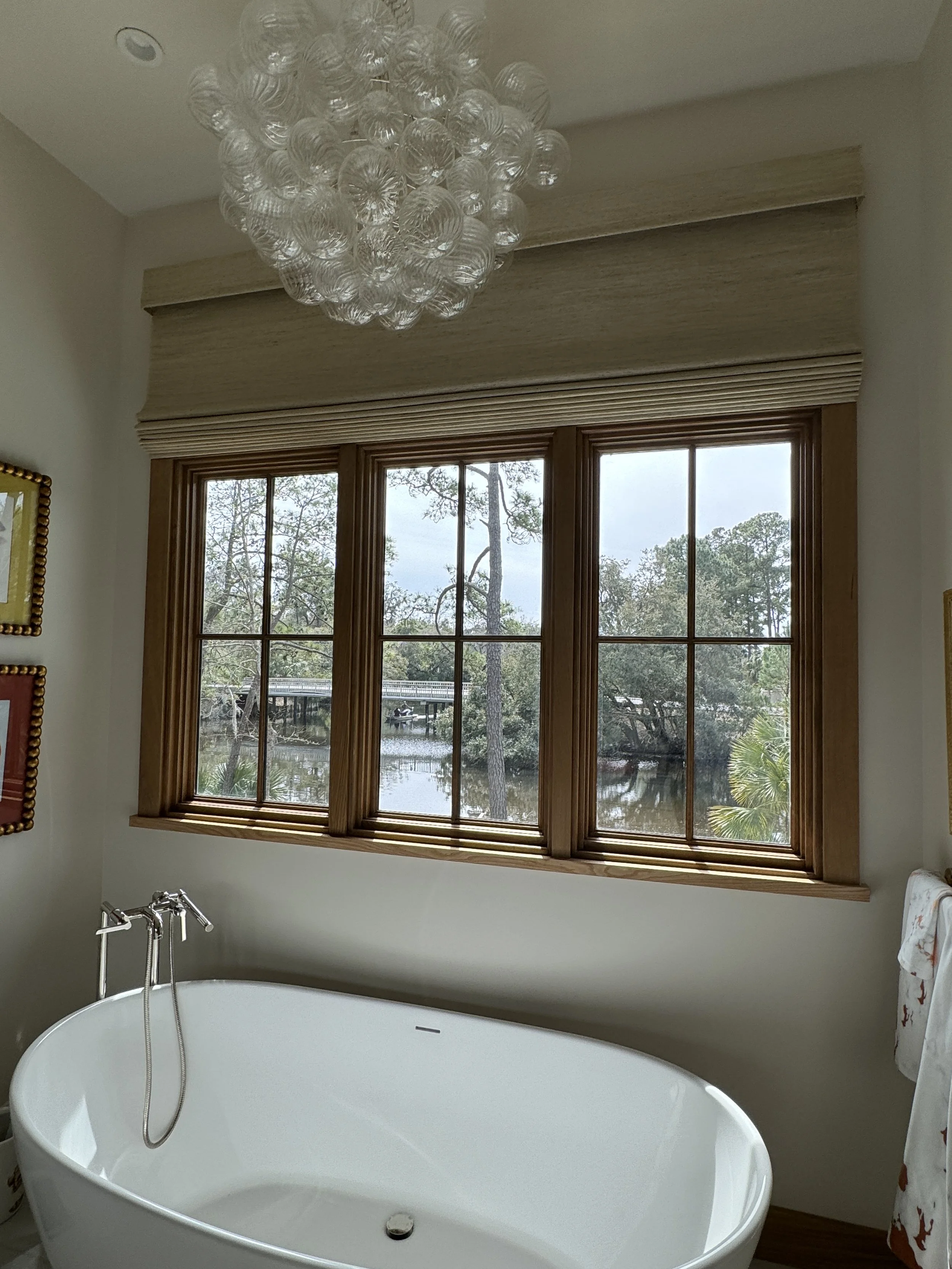   Here, motorized woven wood shades offer privacy and convenience for this challenging to reach window.  