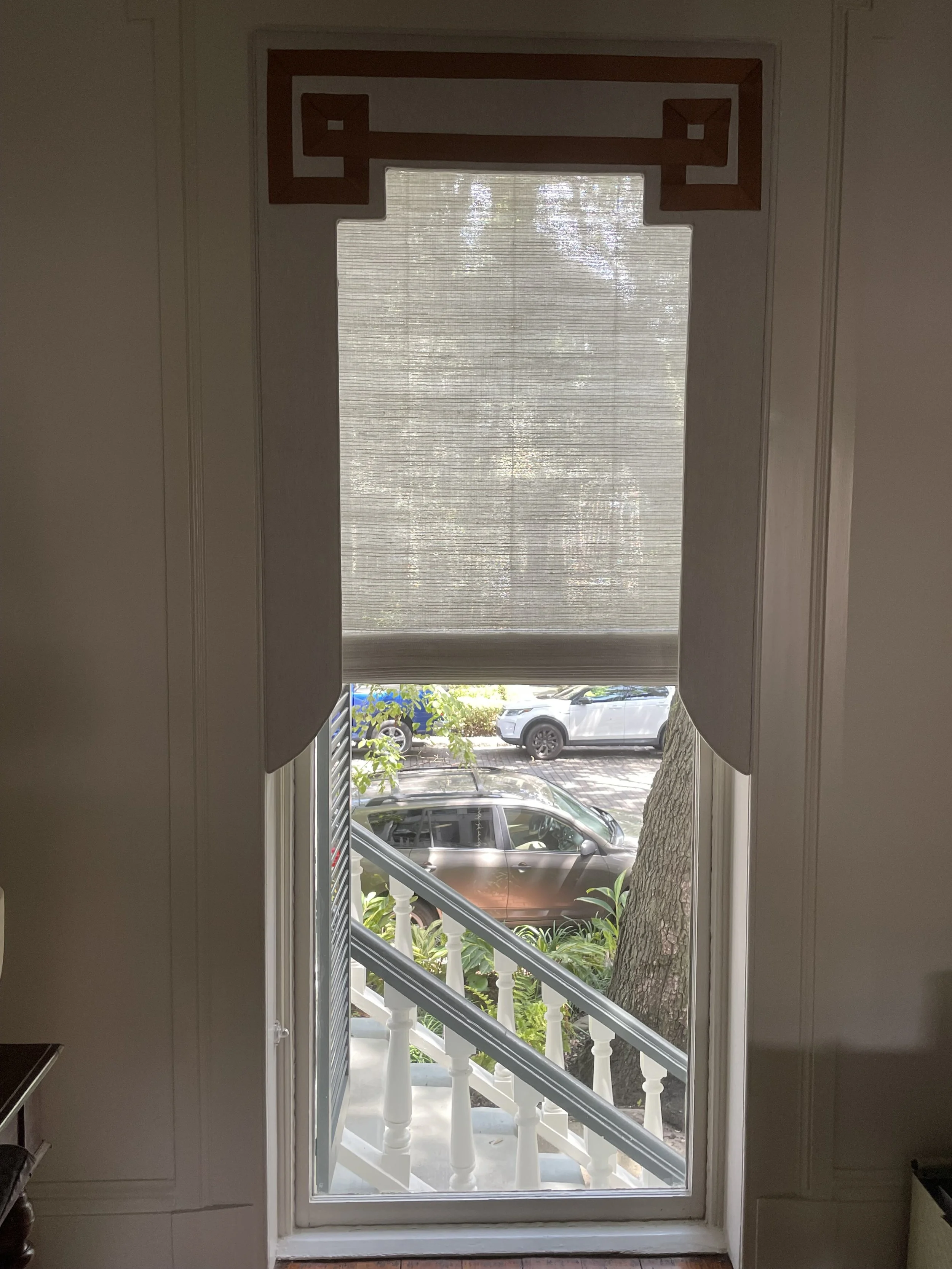 This lambrequin - a traditional style of cornice with historic routes - is layered over a woven wood shade.