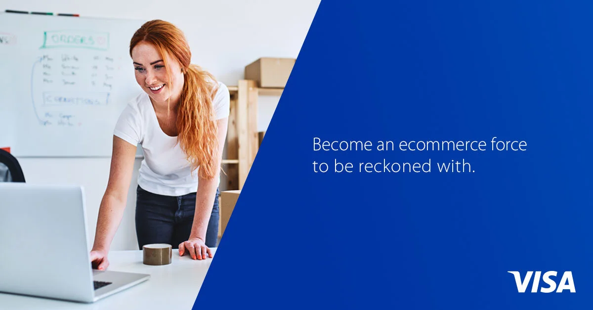 Visa digital banner of a woman with red hair leaning over a desk with a laptop in an office, smiling, with a whiteboard in the background, and a blue overlay on the right side with white text and a Visa logo.