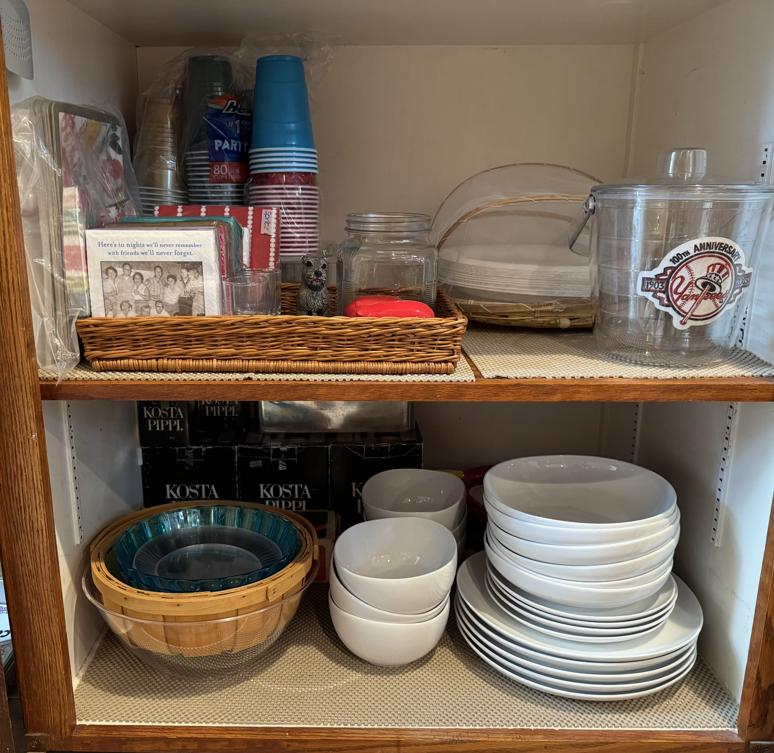 Kitchen cabinet with glass bowls, white bowls, and various kitchen items on shelves.