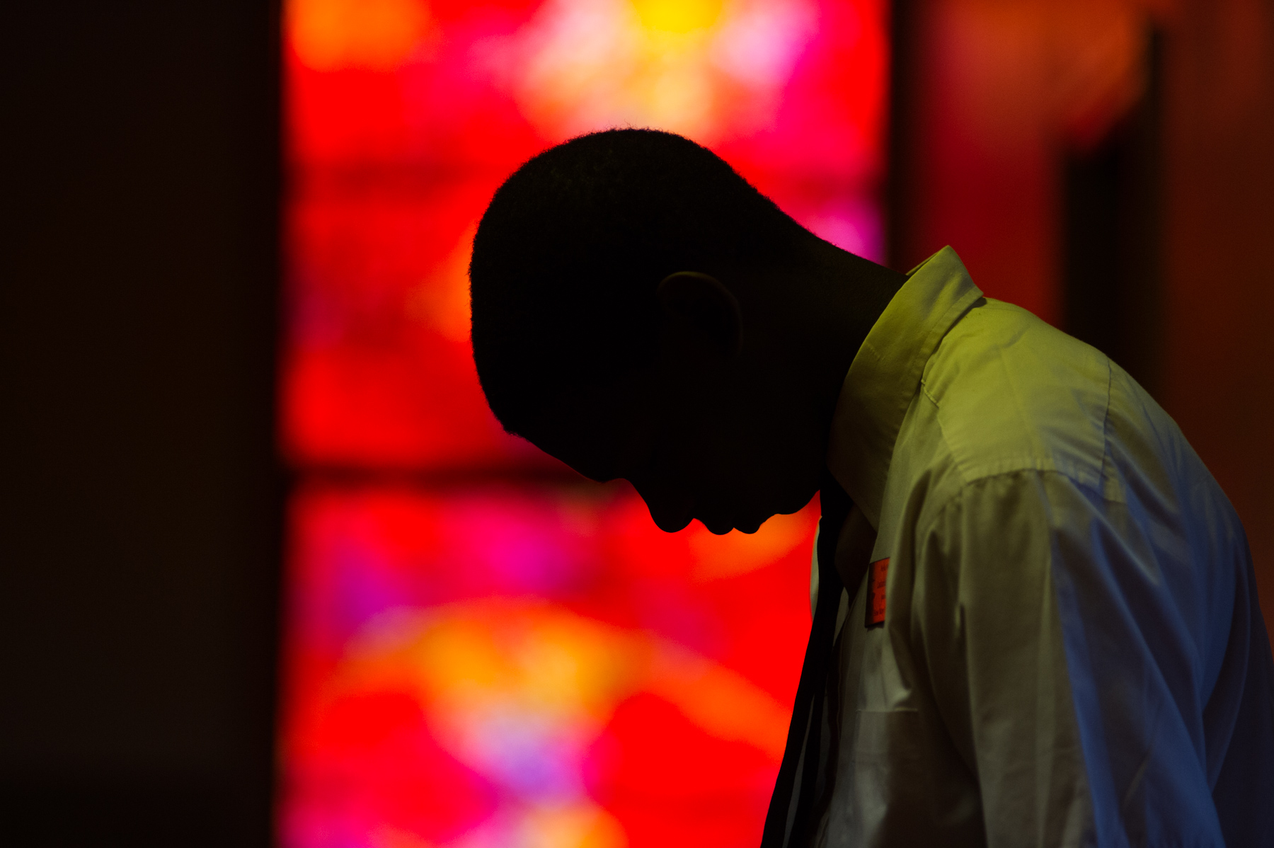 A teenage usher bows his head for prayer during church services.