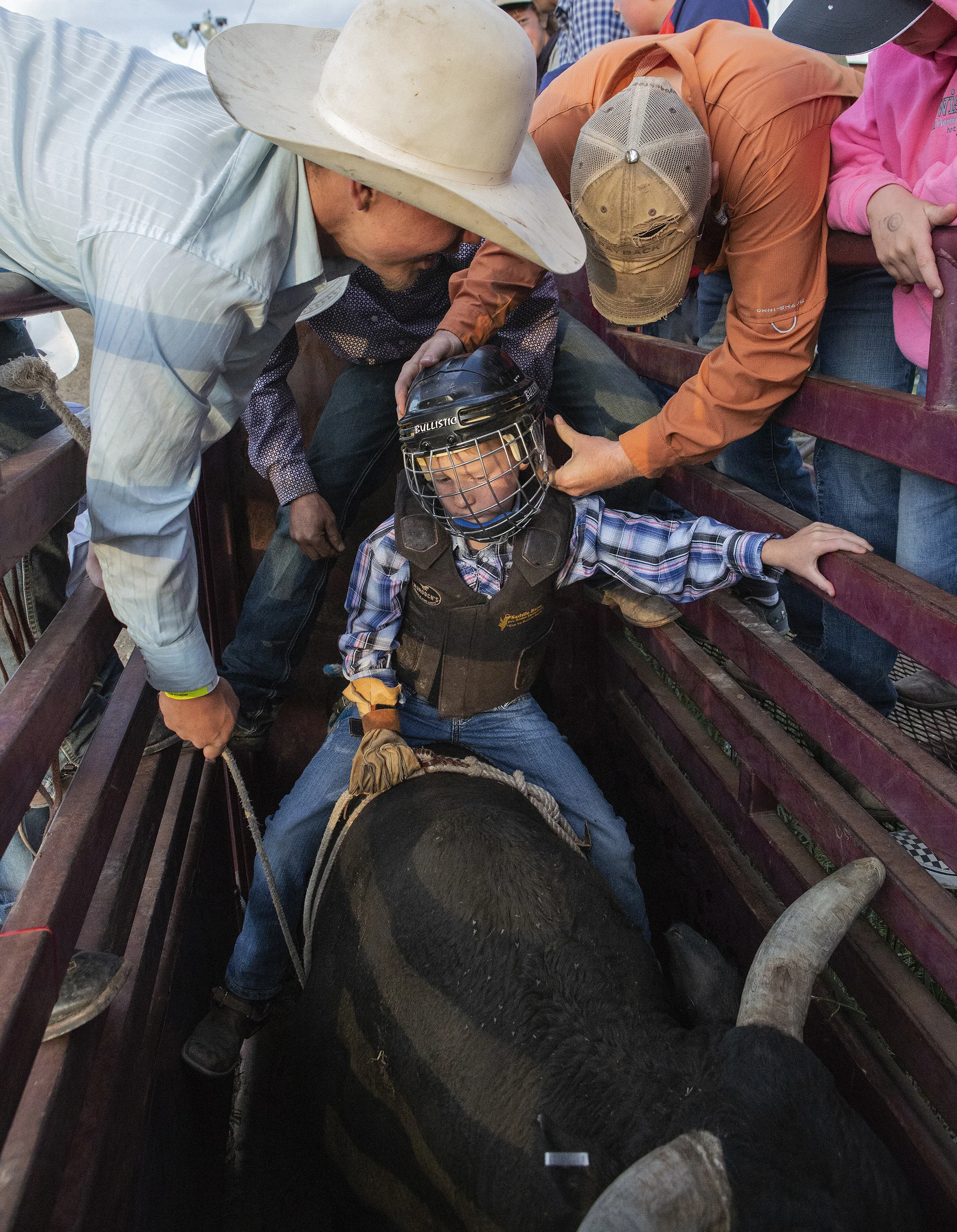  A group of cowboys help Kollin Gustitis, 8, of Chinook, prepare for a bull ride during rodeo events at the Great Northern Fair on Thursday, July 18, 2019 in Havre, Montana. 