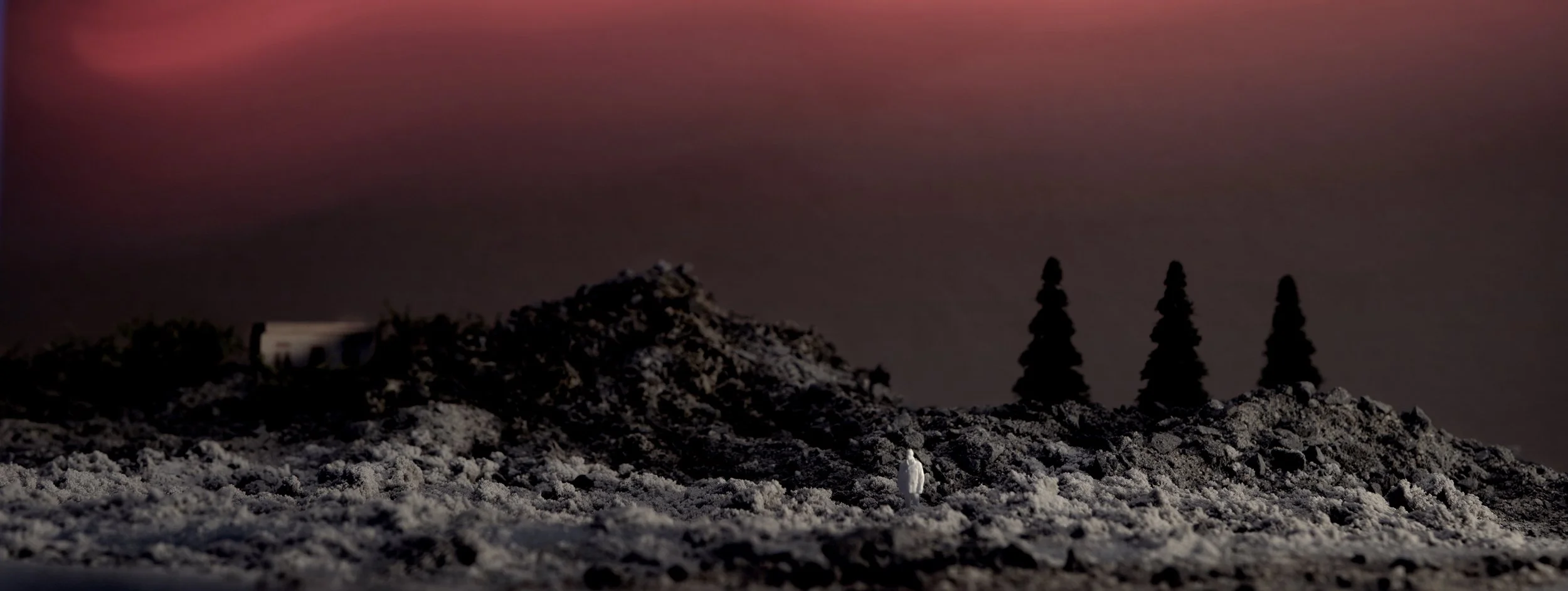 Dystopian almost other worldly landscape with a male figurine looking towards the camera in the back a Russian wooden house.