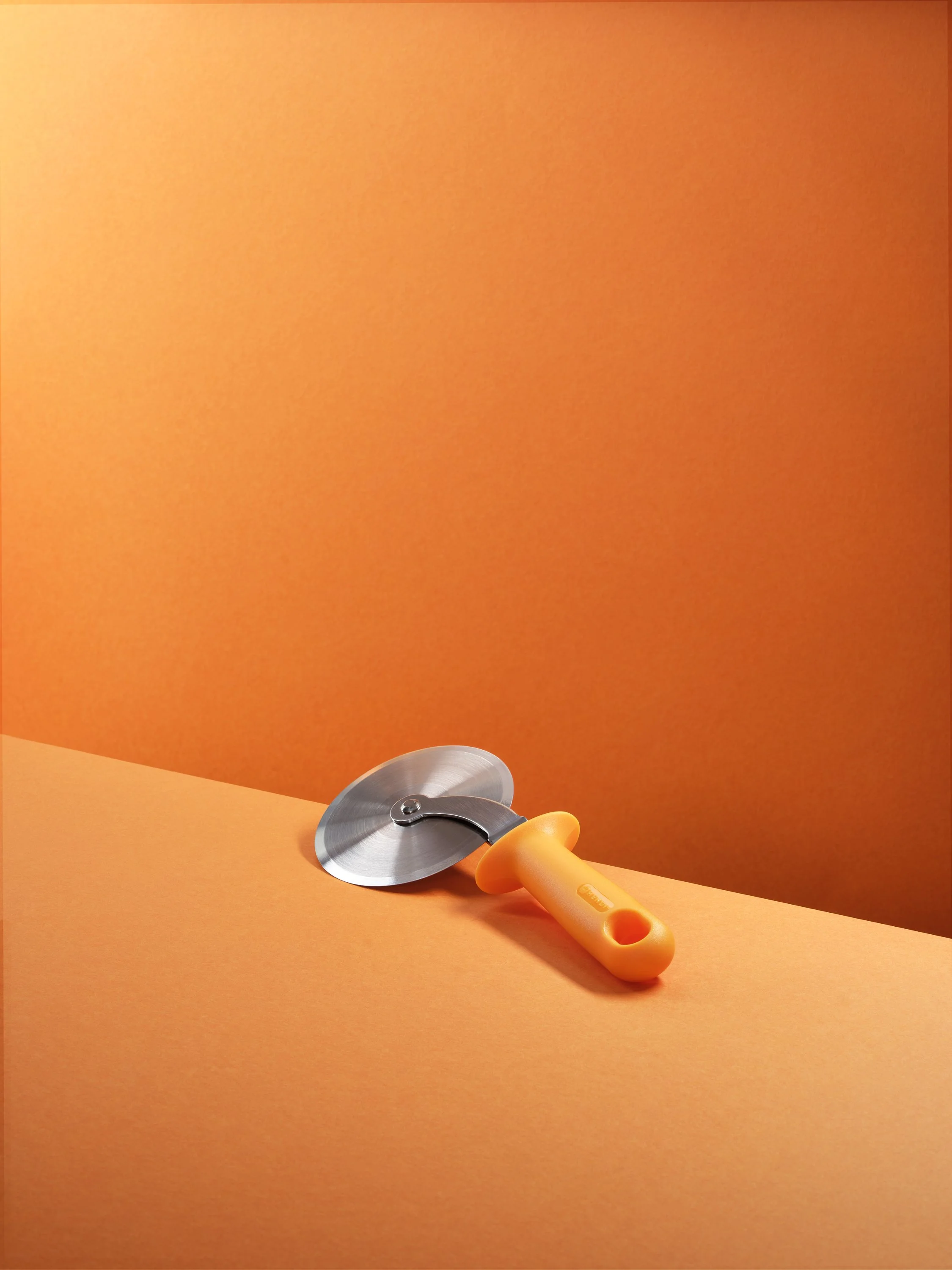 an abstract image of a pizza slicer on a bright orange background