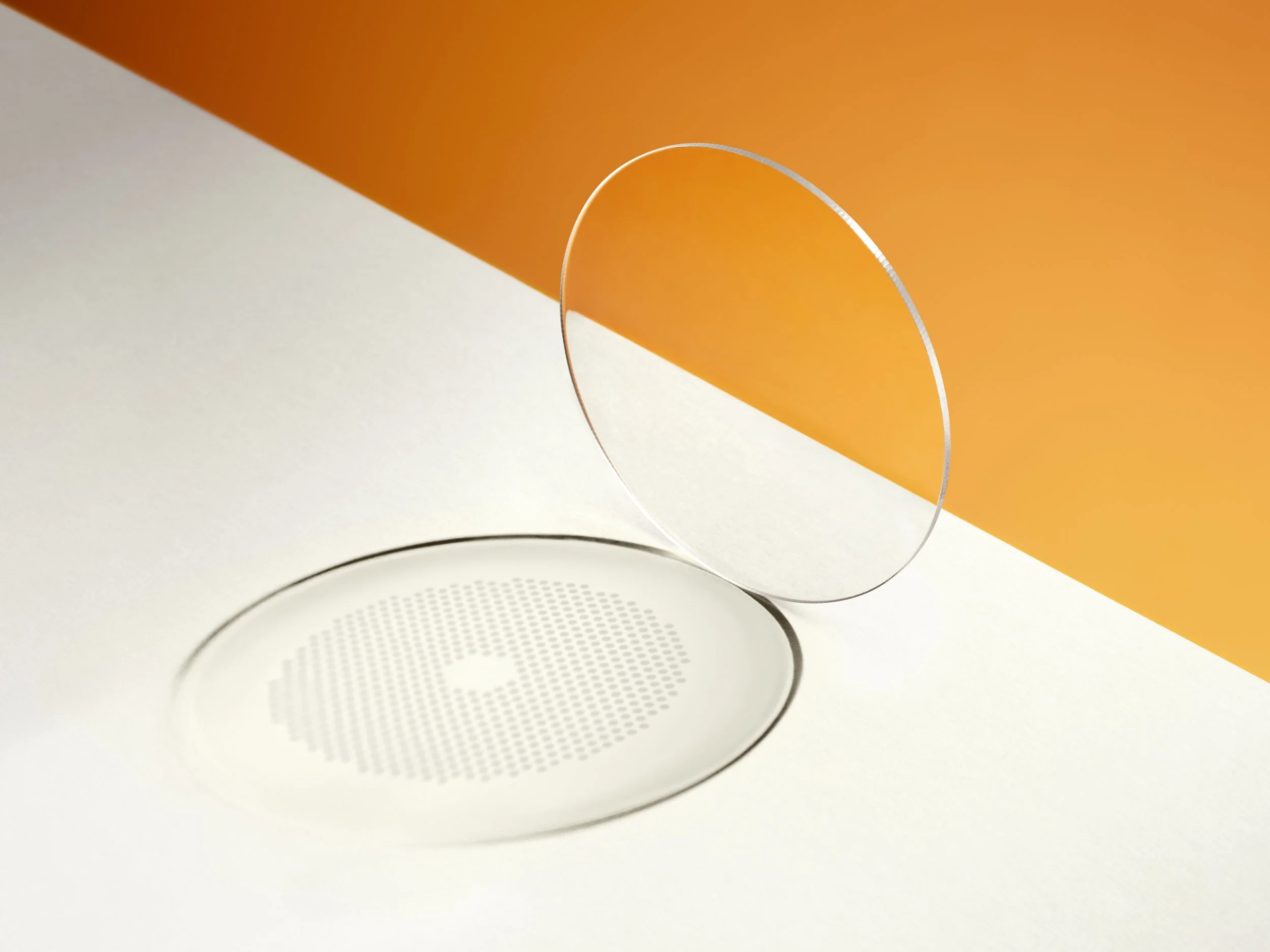 an abstract image of a lens with special engraving shown in the shadow on a bright orange and grey background
