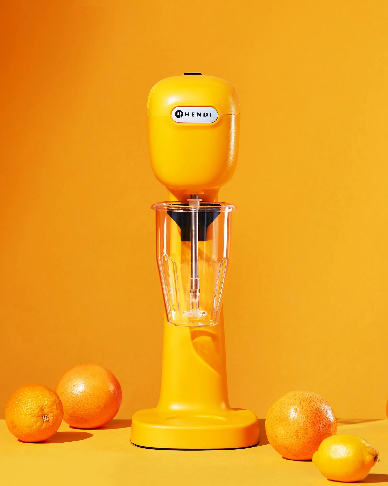 An abstract image of a milkshake maker surrounded by oranges on a bright orange background.