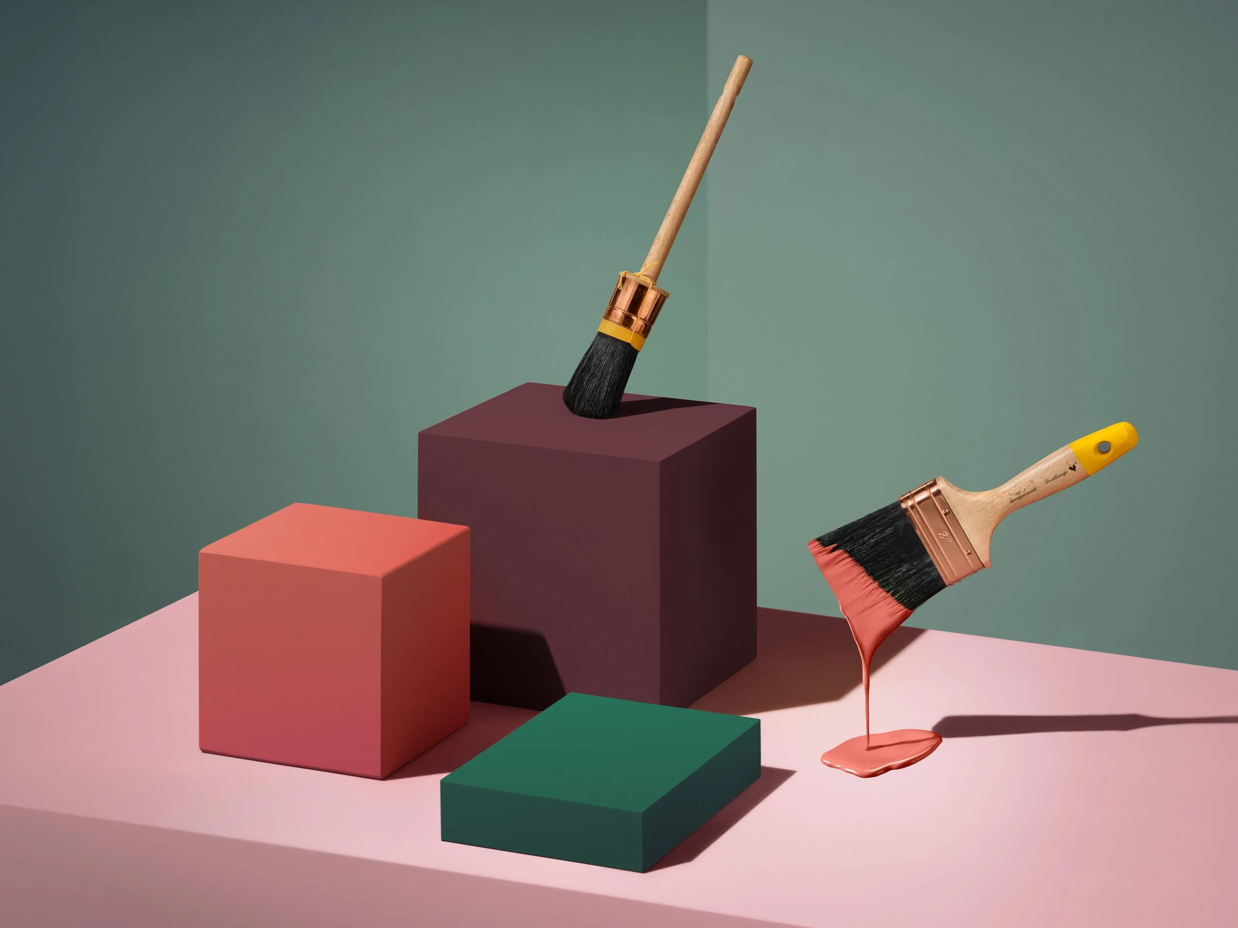 Colorful display of paint brushes, some dipped in pink paint, arranged on pastel-colored blocks and surfaces against a muted green background.