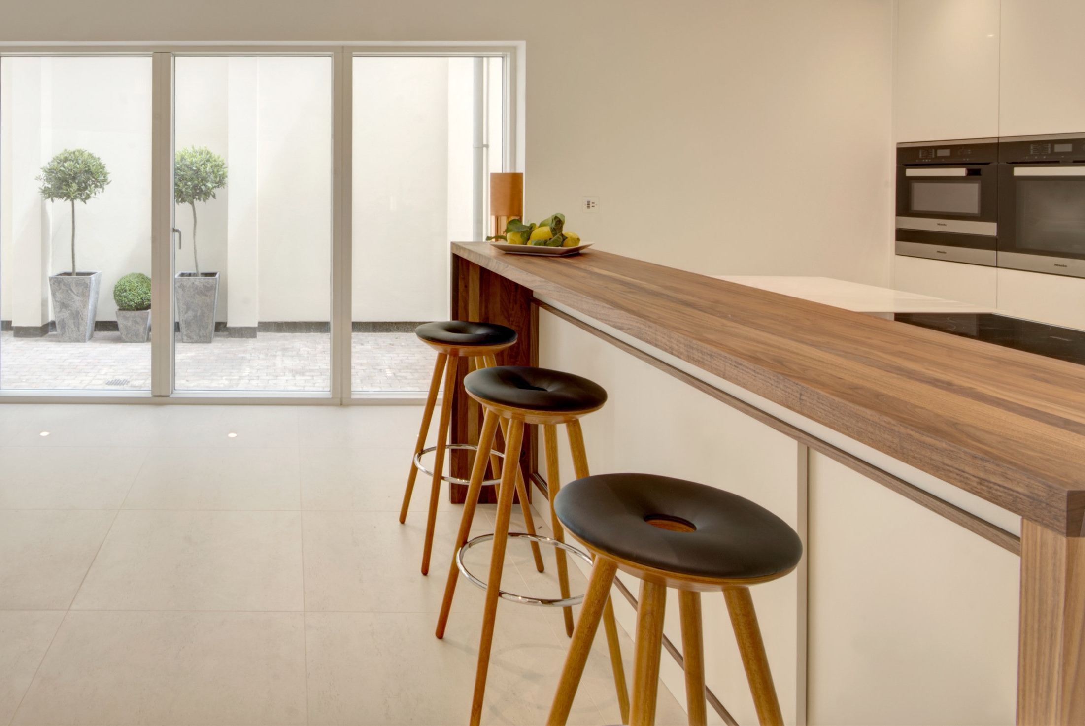 Kitchen design for contemporary development featuring island unit with walnut bar.