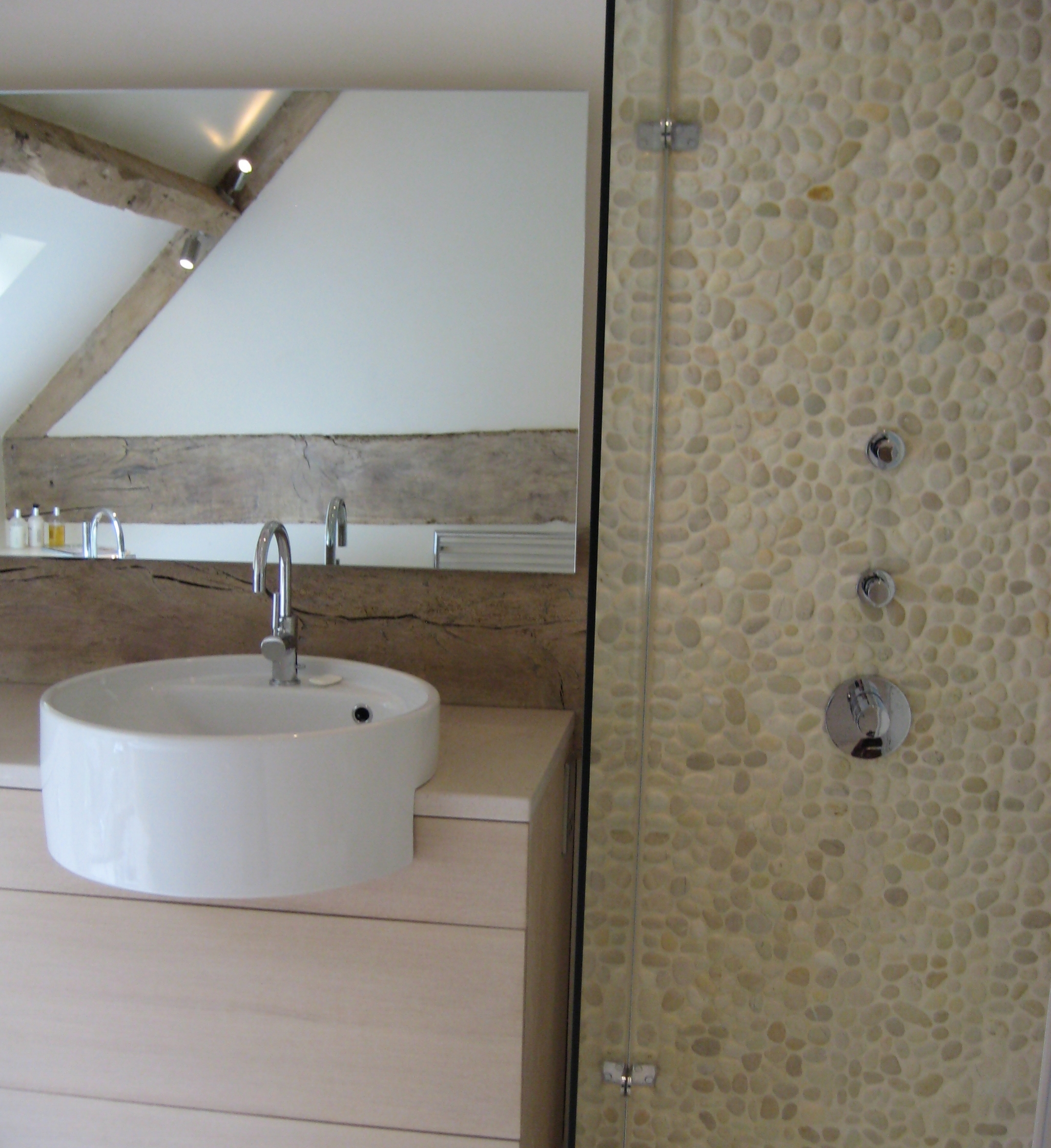 Contemporary bathroom design with semi inset basin and feature shower cubicle with pebbles.