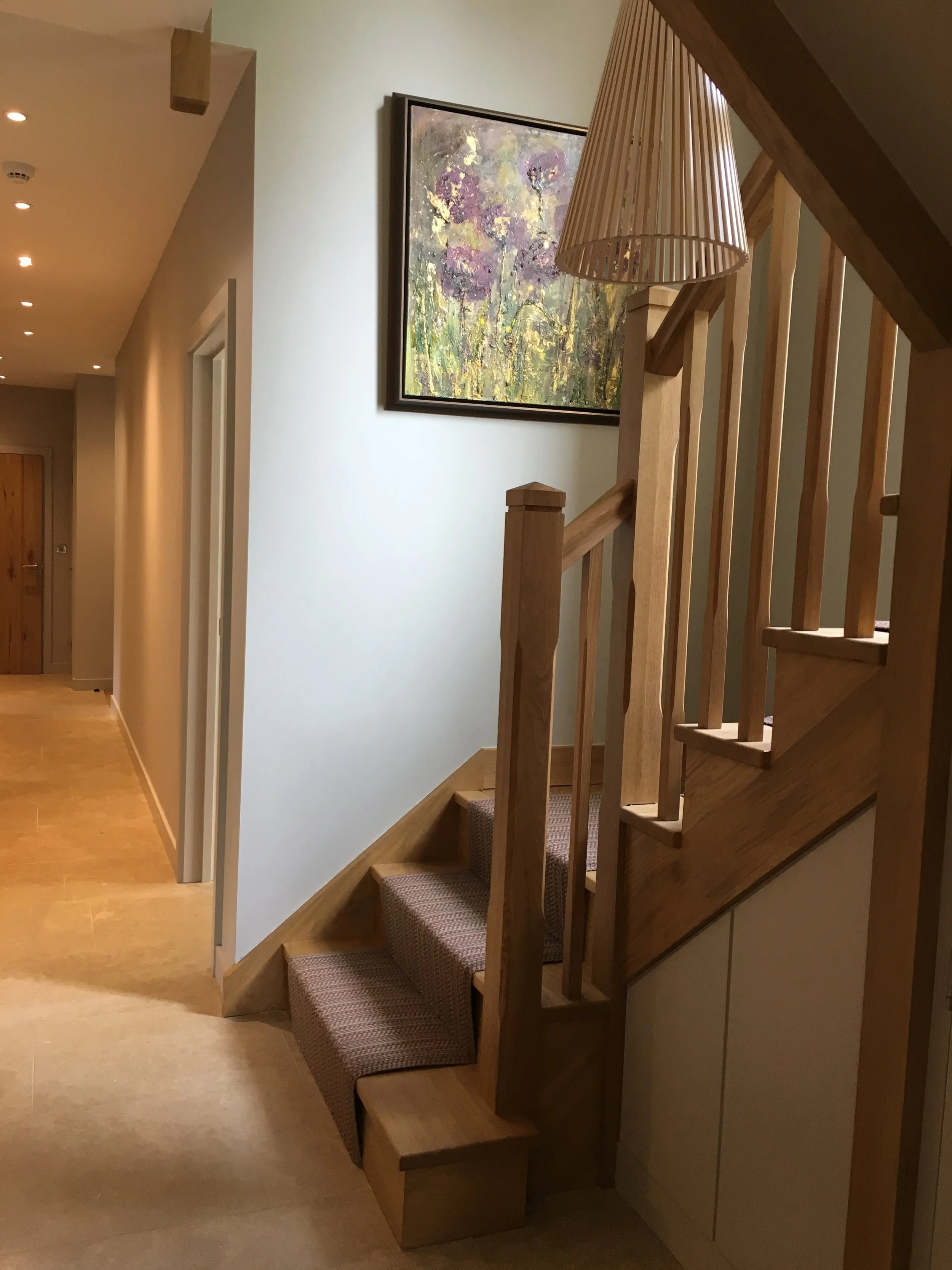 Oak staircase with runner, modern timber pendant light and oil painting.