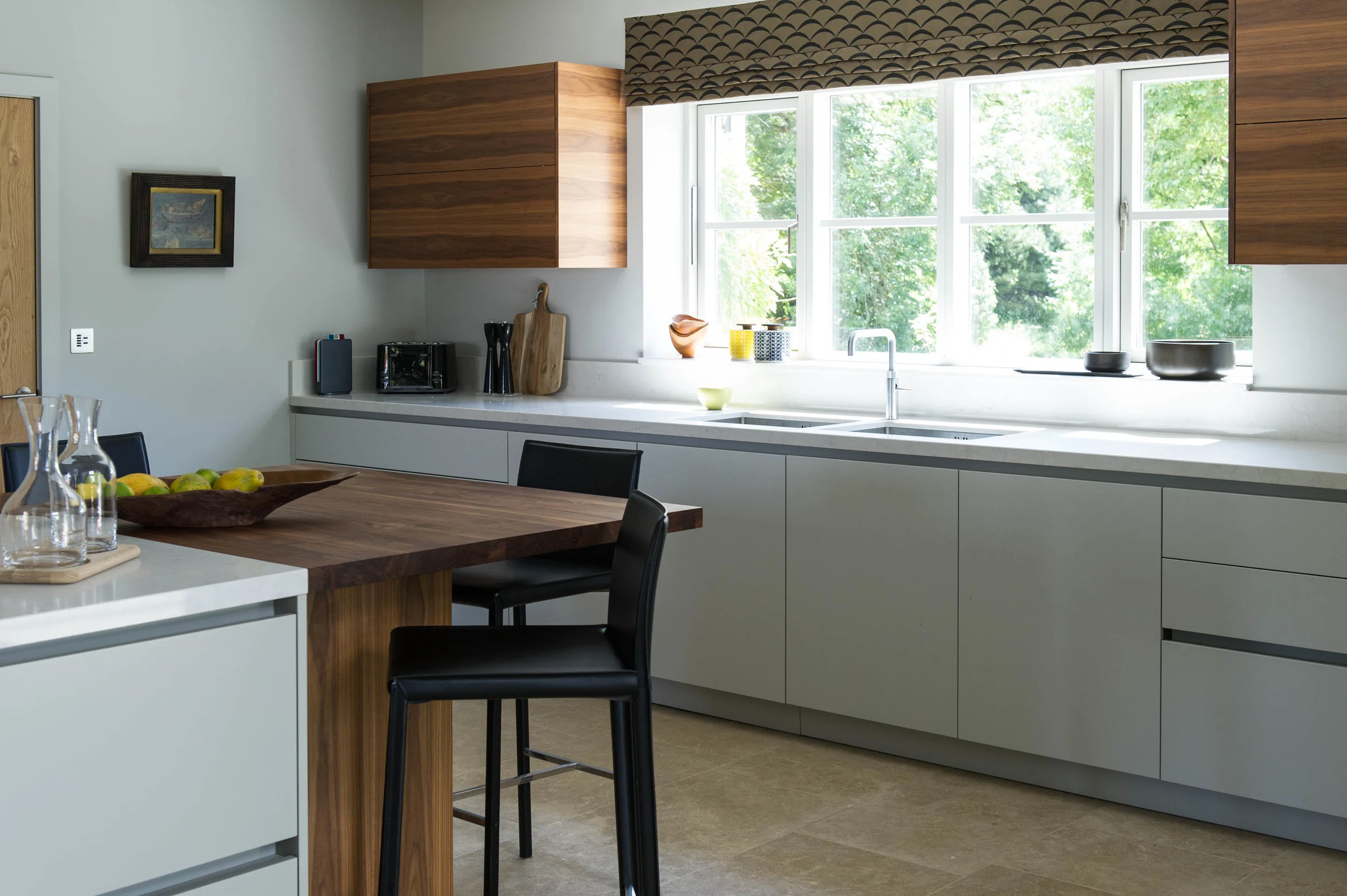Kitchen design with painted base units, walnut wall units and island unit with bar stools.
