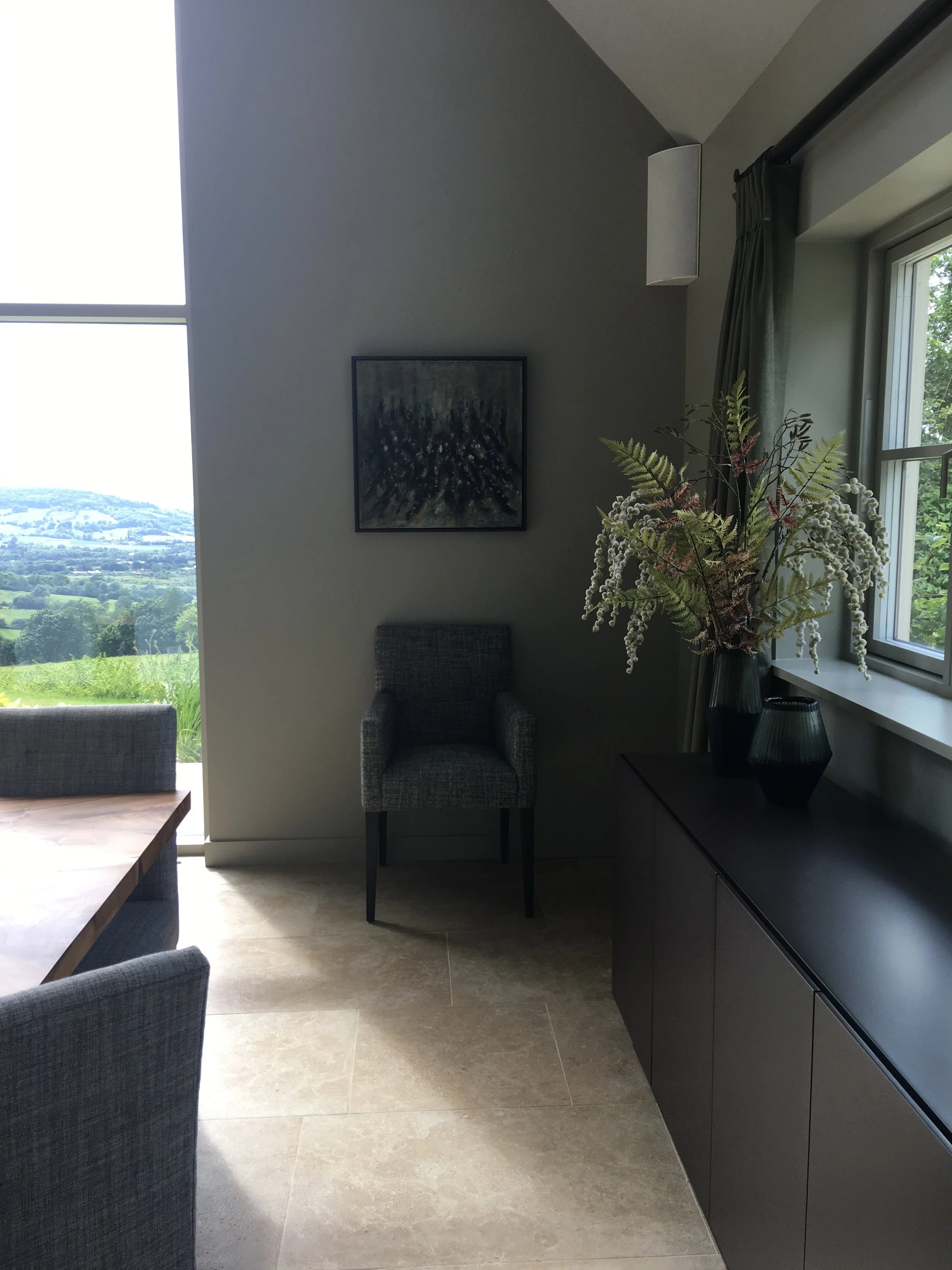Grey, upholstered carver and sideboard dressed with vase of flowers.