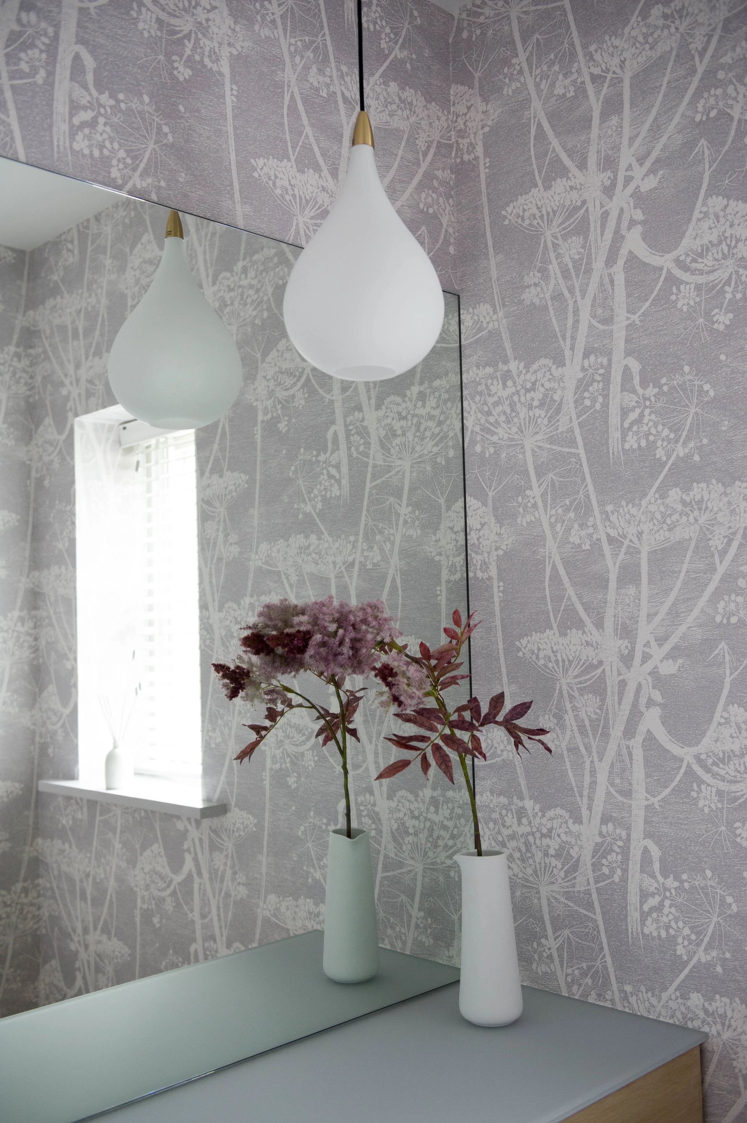 Bathroom design with pretty, botanical wallpaper and vase of flowers.