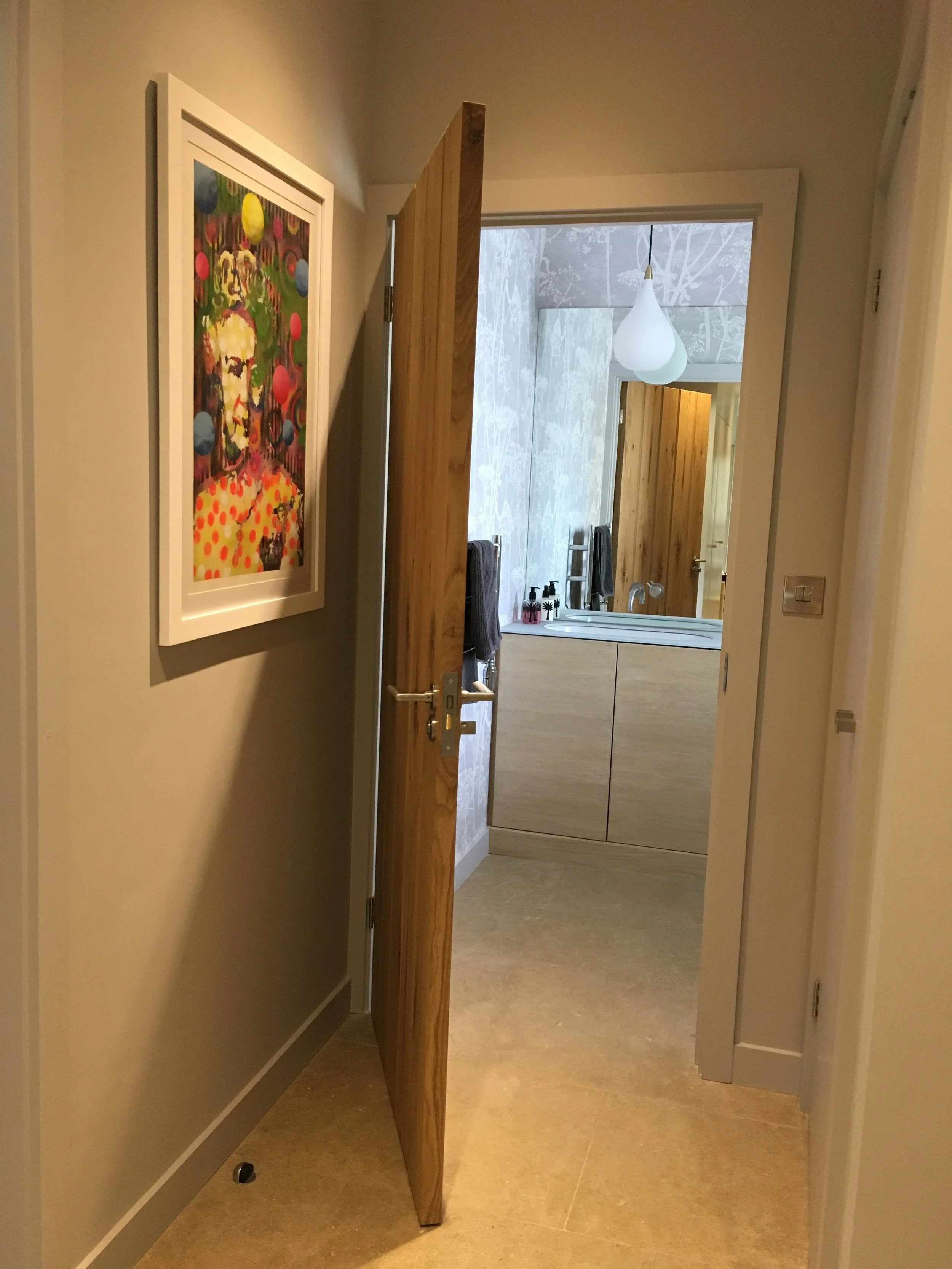 View into cloakroom through doorway. Contemporary artwork on wall.