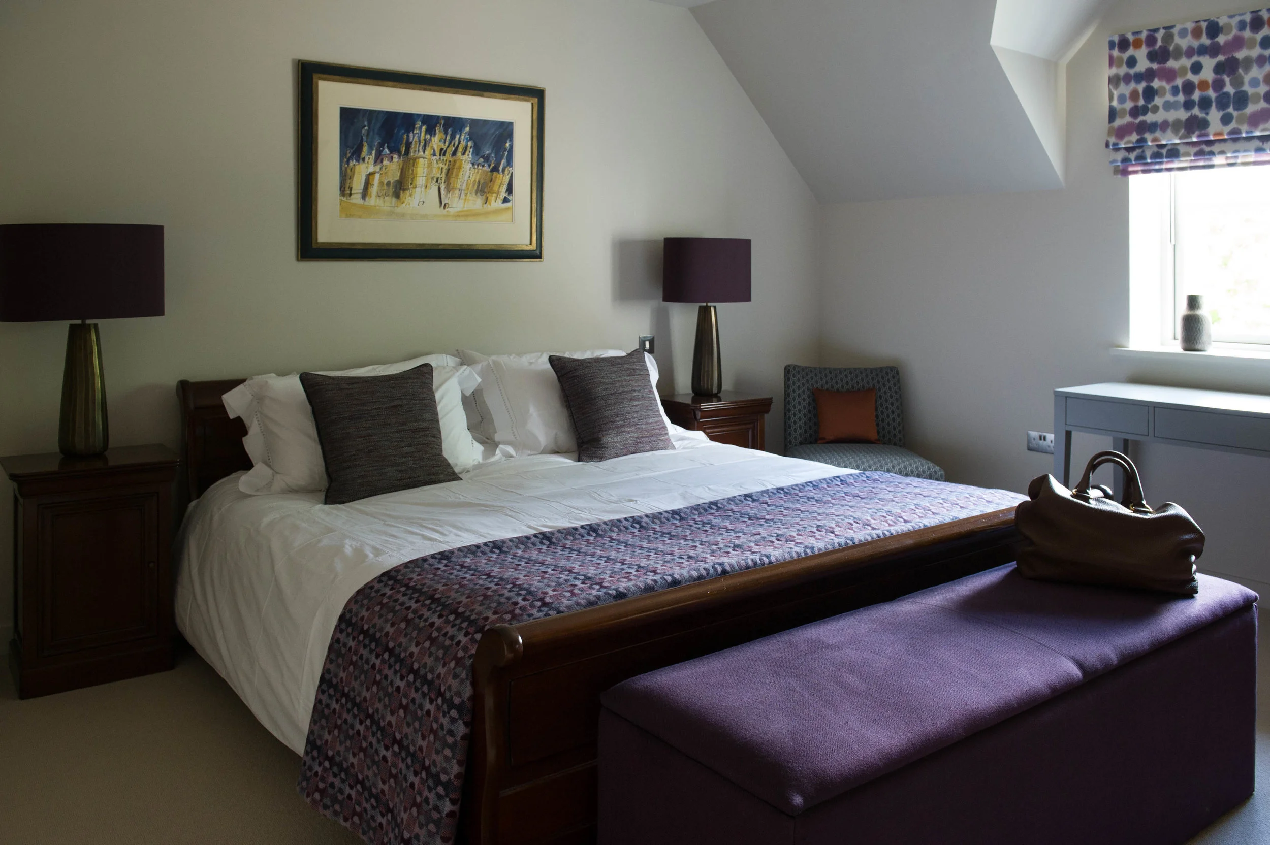 Bedroom in purple and blue tones with orange accents. Timber sleigh bed and bedside tables with table lamps, blanket box, bedroom chair and dressing table. By Joseph Interior Design, Cheltenham.