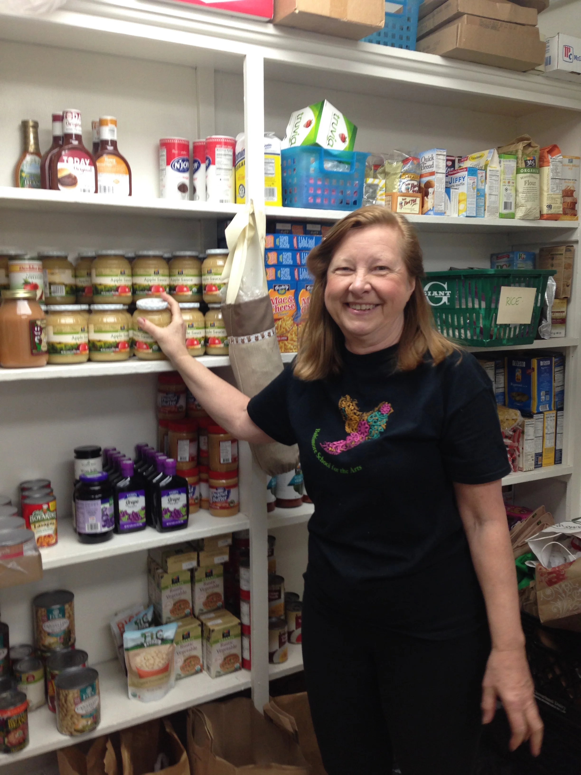 Coleen, one of our regular volunteers, prepares the food pantry for members by stacking the shelves.