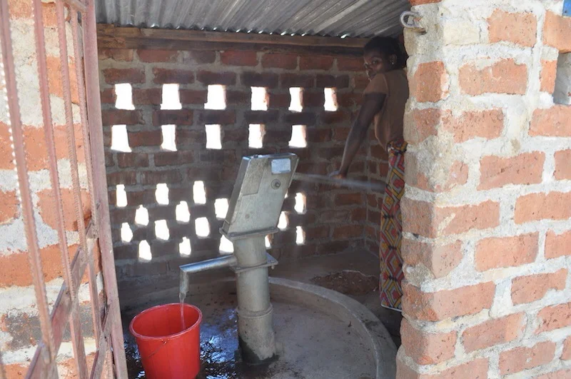 A woman pumps water in Cohombe Village near Chipata