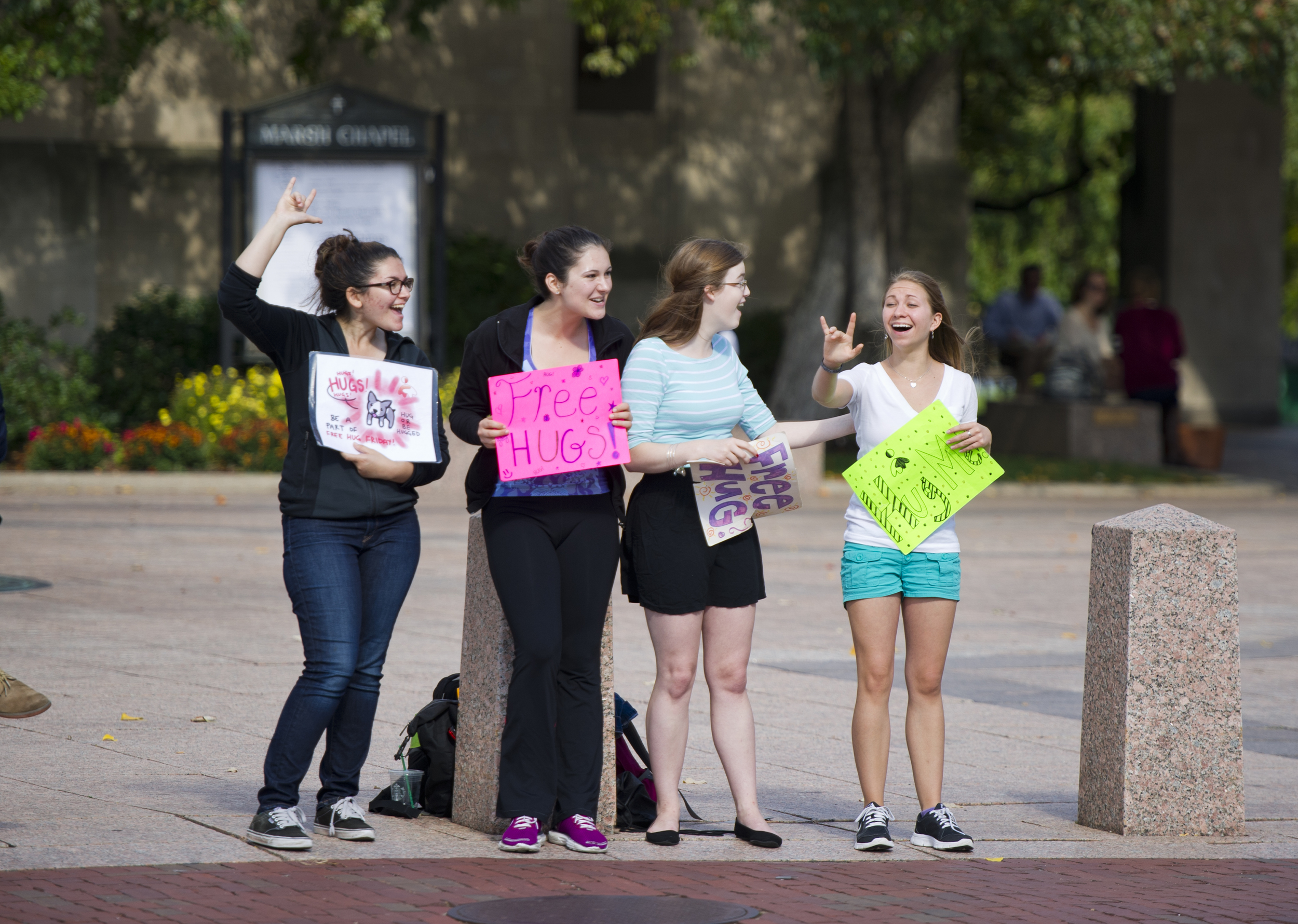 When a passerby flashes them the ASL sign for "I love you" I Embrace You president Melanie Kirsh (CAS'16), far left, &nbsp;and Chelsea Hammond (SED17), far right, react by doing the same at Marsh Plaza October 17, 2014 . Between Kirsh and Hammond an