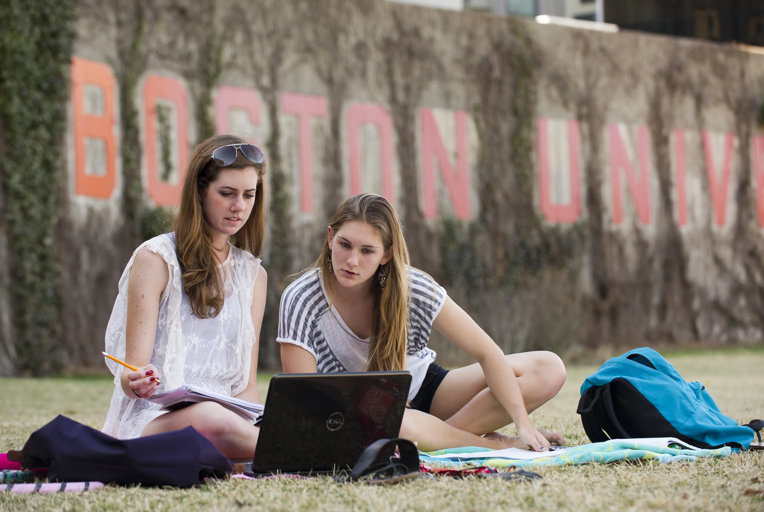 Kelsey Young (COM'15), left, and Boone Saunders (CAS'15) study statistics for class in the shade on Nickerson field. They had started in the sun, the two said, but it got too hot. Nickerson field March 22, 2012. Photo by Cydney Scott for Boston University Photography