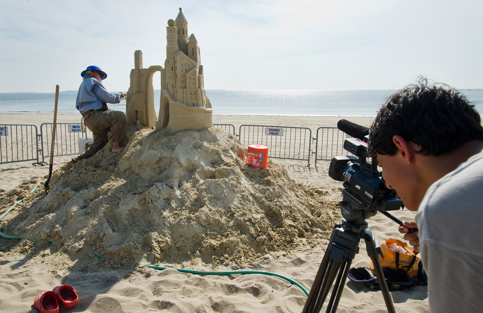  COM's Academy of Media Production (AMP) student &nbsp;Dyan Fam, 15, of Winchester collects footage of The Amazin' Walter McDonald of Texas as he creates his sand sculpture. COM Assistant Professor Chris Cavalieri brought the students to the Revere B