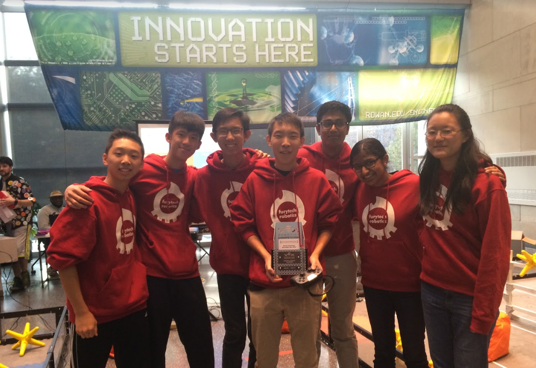 Team 765A is shown with their Excellence Award, which is presented to a team based on their quality of robot, skills score, design notebook, and their teamwork/collaboration.