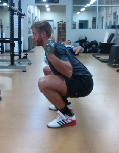Hamstring and calve contact should be made to ensure full-depth is being achieved. The chest should remain tall without the lower back rounding. Toes angled slightly out, while driving the knees out to create a hole to sit into. Head is in a neutral posture, and arms are tight enough in on the bar to create a shelf with the traps for the bar to sit on (this picture is a high-bar Olympic styled squat).