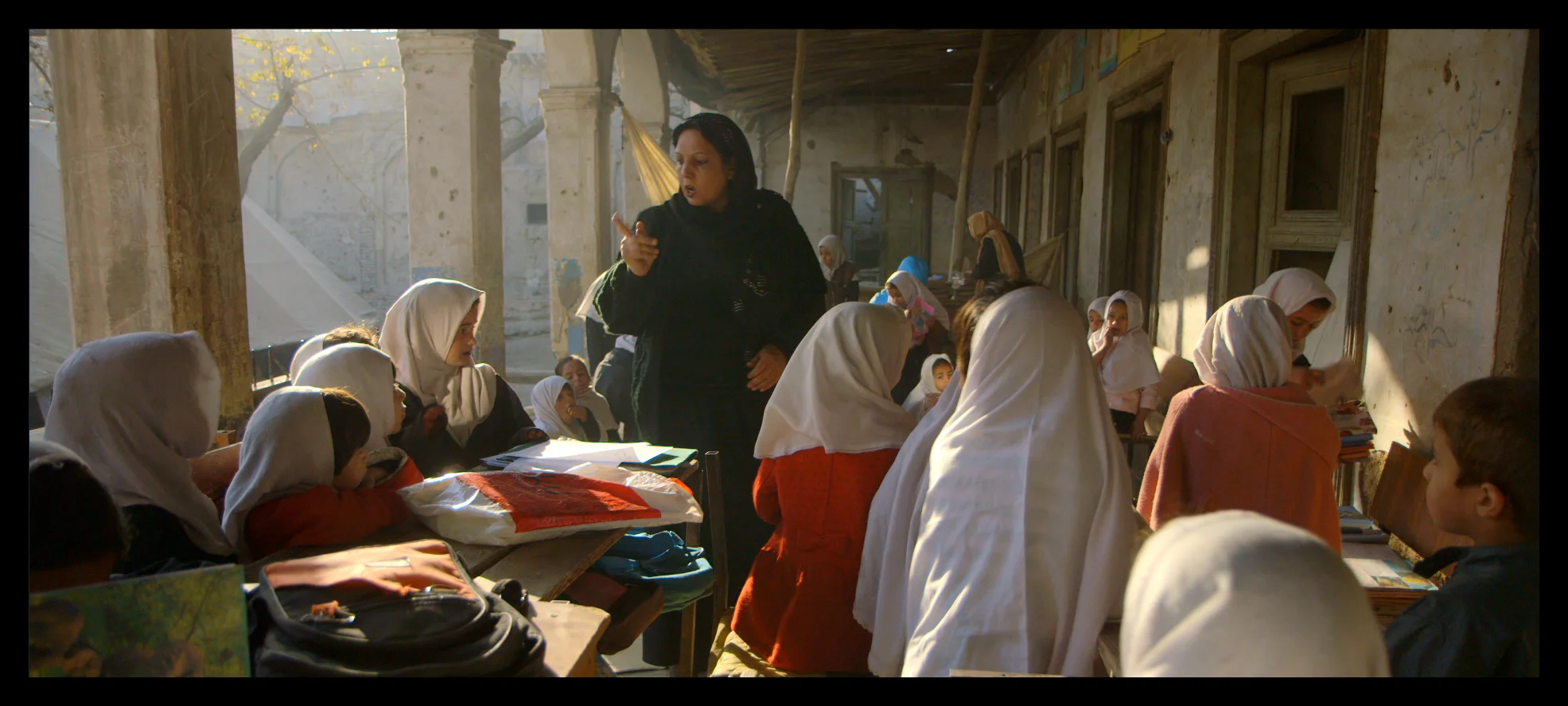 Film still: A classroom of girls at the original location of the Daqiqi Balkhi school, at the destroyed Gudri mosque