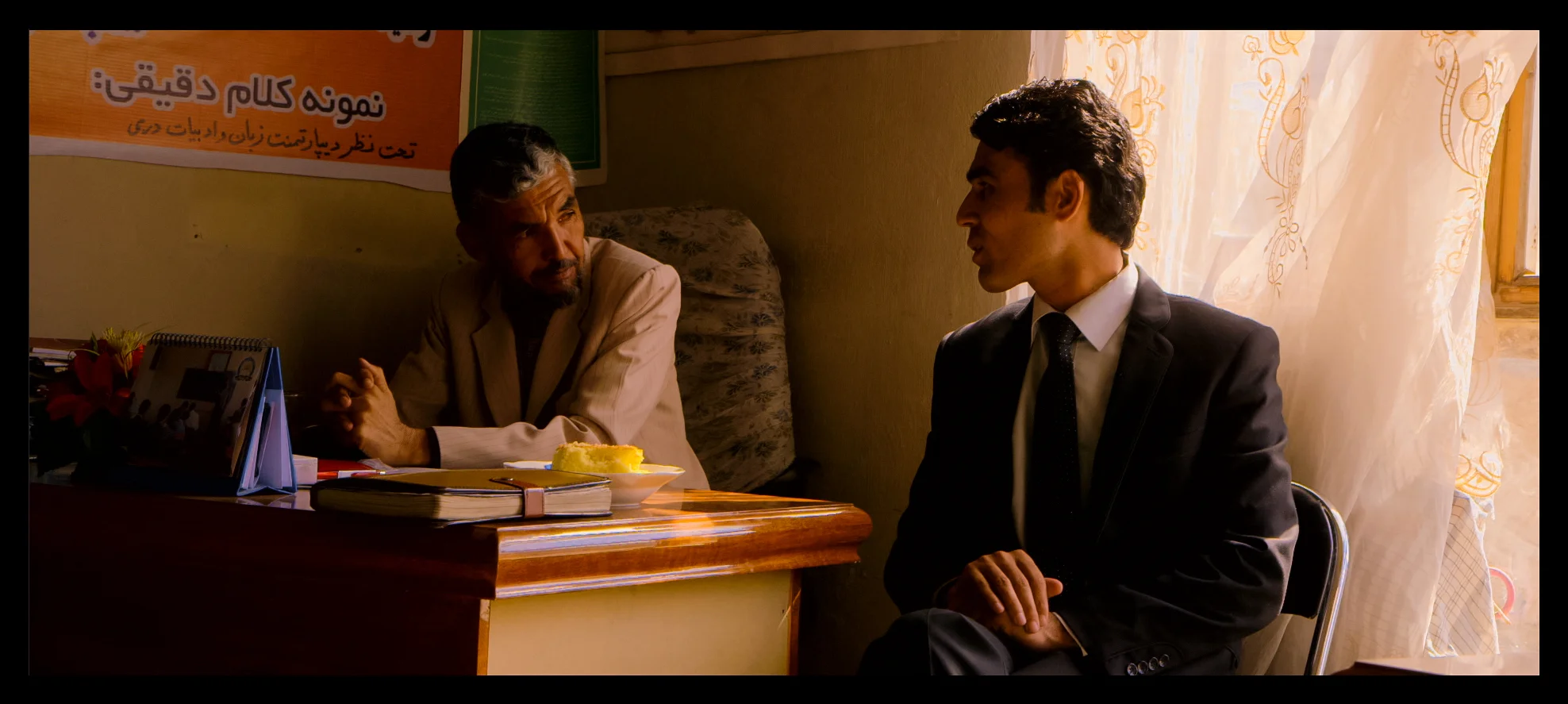 Film still: School principal Faiz Mohammed (left) speaks with a colleague at the Daqiqi Balkhi school