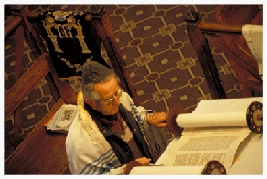 Hermann Gerson, President of Moises Ville's Baron Hirsch synagogue, reads Torah from the bimah, which Moises Ville’s Jewish ranchers fashioned like an ornate corral, with hand-sanded, stained and varnished logs at cross-angles. Hermann briefly trained to be a rabbi in Germany before his family fled from the Nazis to the Argentine Pampas, where he has been a rancher ever since.