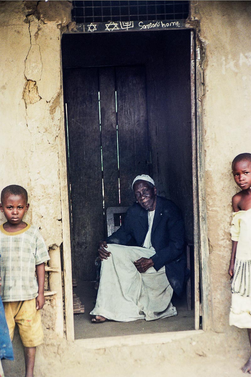 Samson Magombe is the ninety year-old former spiritual leader of the Abayudaya community. After community founder, Semei Kakungulu, died in the late 1920s, young Magombe became "Rabbi" of the community, leading prayer services at the Namanyonyi synagogue and teaching generations of Abayudaya children about Judaism. In 1976, Idi Amin became dictator of Uganda and forbade practice of Judaism, frightening members of the Abayudaya community into either conversion or hiding. Two thousand five-hundred of the three thousand Abayudaya converted to Christianity and Islam, and the remaining five hundred continued to practice in private, lighting candles in their homes rather than in synagogue, reciting the Shema in a whisper. After Amin was overthrown in 1979 the Abayudaya emerged from hiding to practice once again in public.