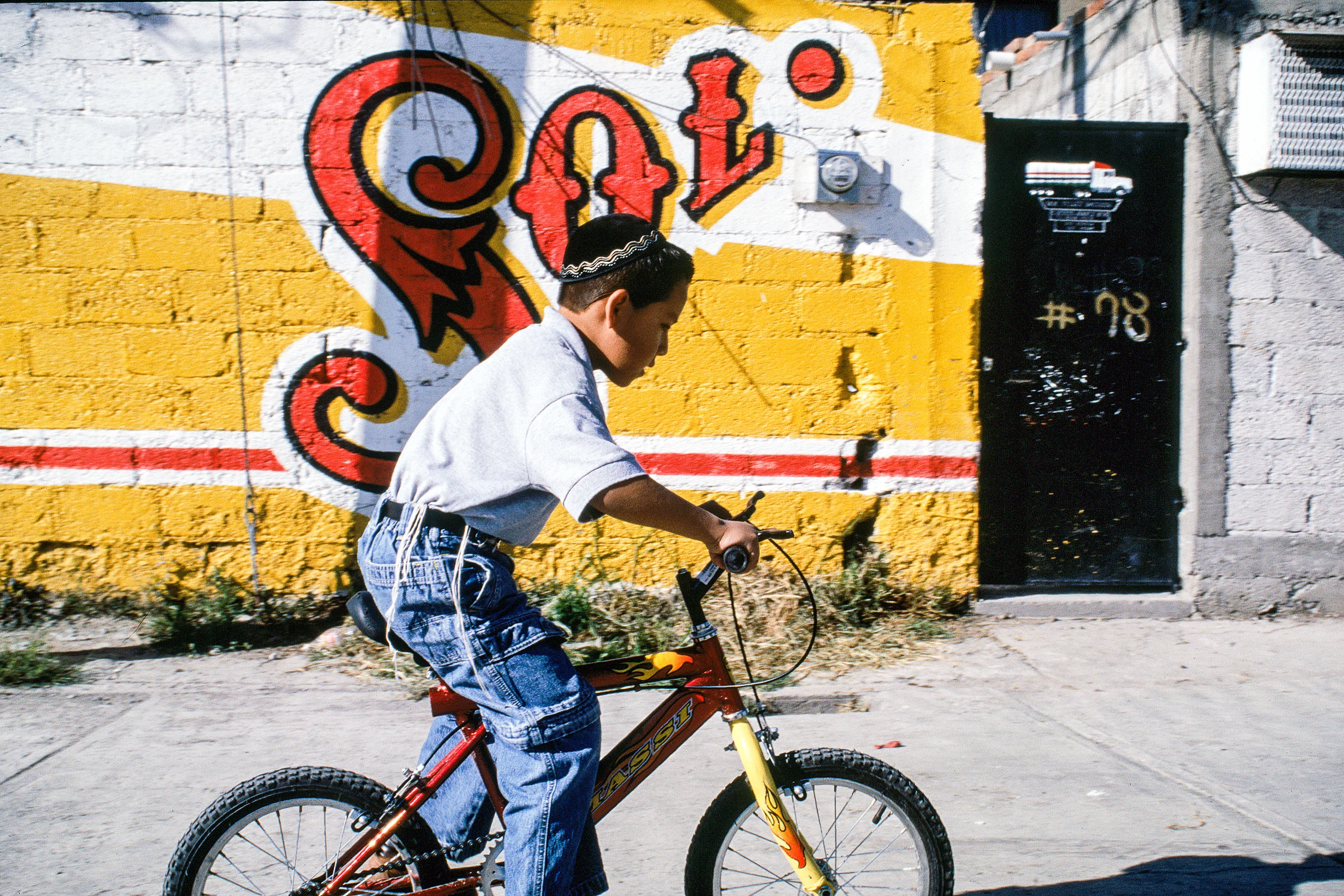 Though he is growing up less than two hours north of one of the world's largest cities, young Shmuel, age 6, is not afraid of strangers. He rides, in the hours before Shabbat, down the middle of the street, between the brightly-painted stucco walls, on his shiny first bicycle, which he recently learned to ride. Skidding to a stop before a Jewish visitor, Shmuel's tzitzit dangling at his sides, his nascent peiyot moist with exertion, he looks up, asking the man, “What size is your kippah ?”
