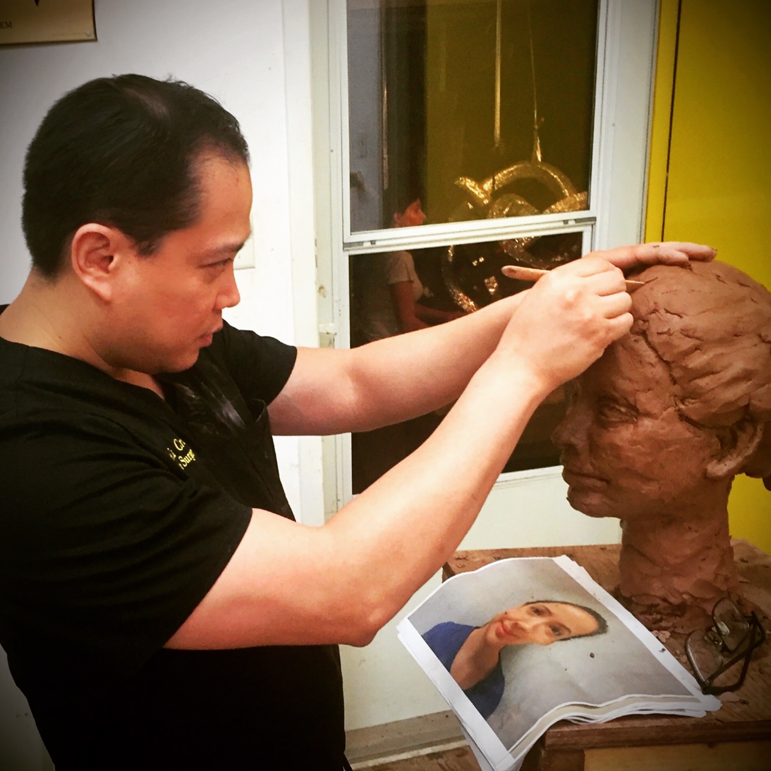 Dr. De La Cruz finishing his portrait sculpture.