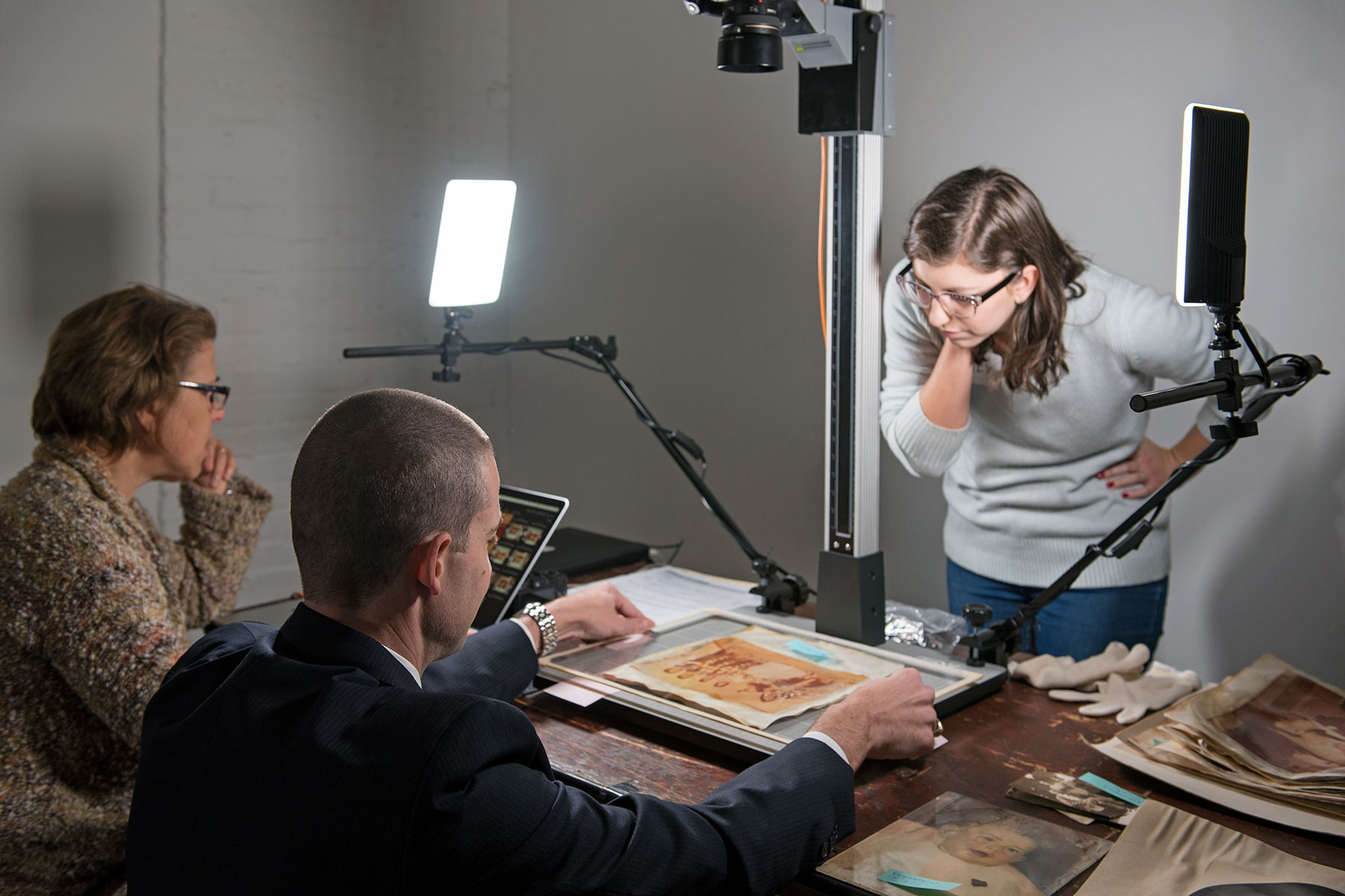 Photographer Gaby Nissen (left) copies a damaged photo, assisted by volunteers Dave Morris and Emily Ardoin. / photo by Jim Parsons