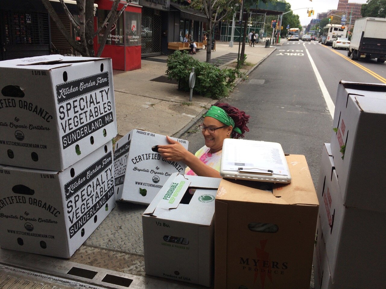 Person pulling boxes off the back of a truck with vantage point of image looking out at street. 