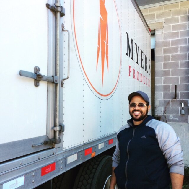 Person standing in front of the Myers Produce logo on the side of a box truck. 