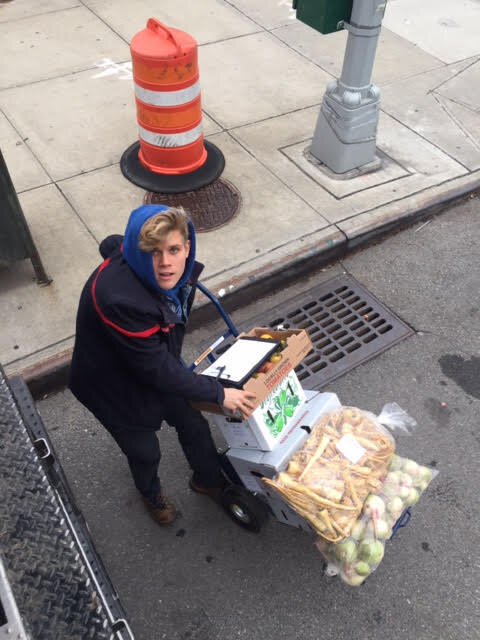 Person with a hand-truck full of vegetables on their way for a delivery in NYC. 