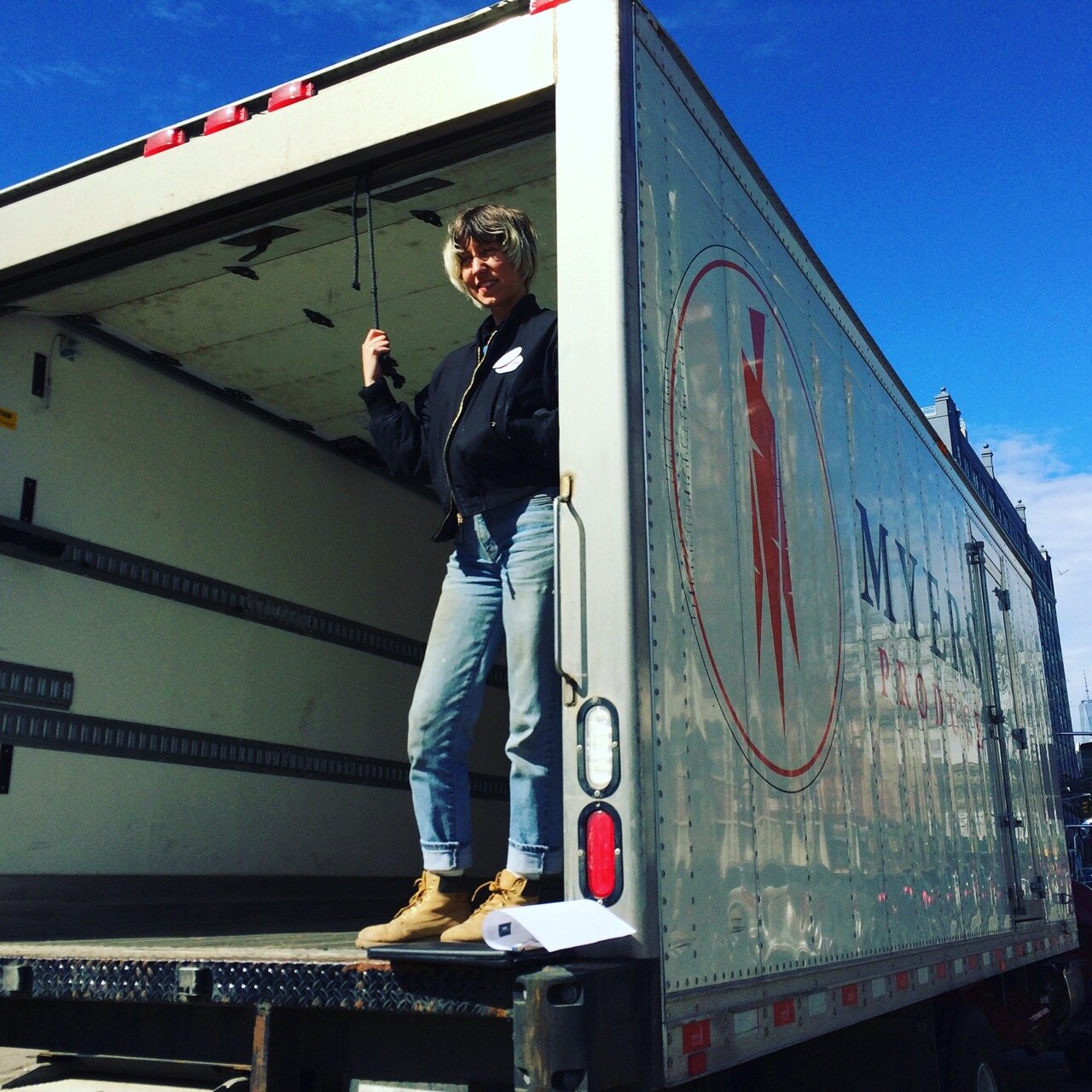 Person standing in the back of a box truck with a thumbs up.