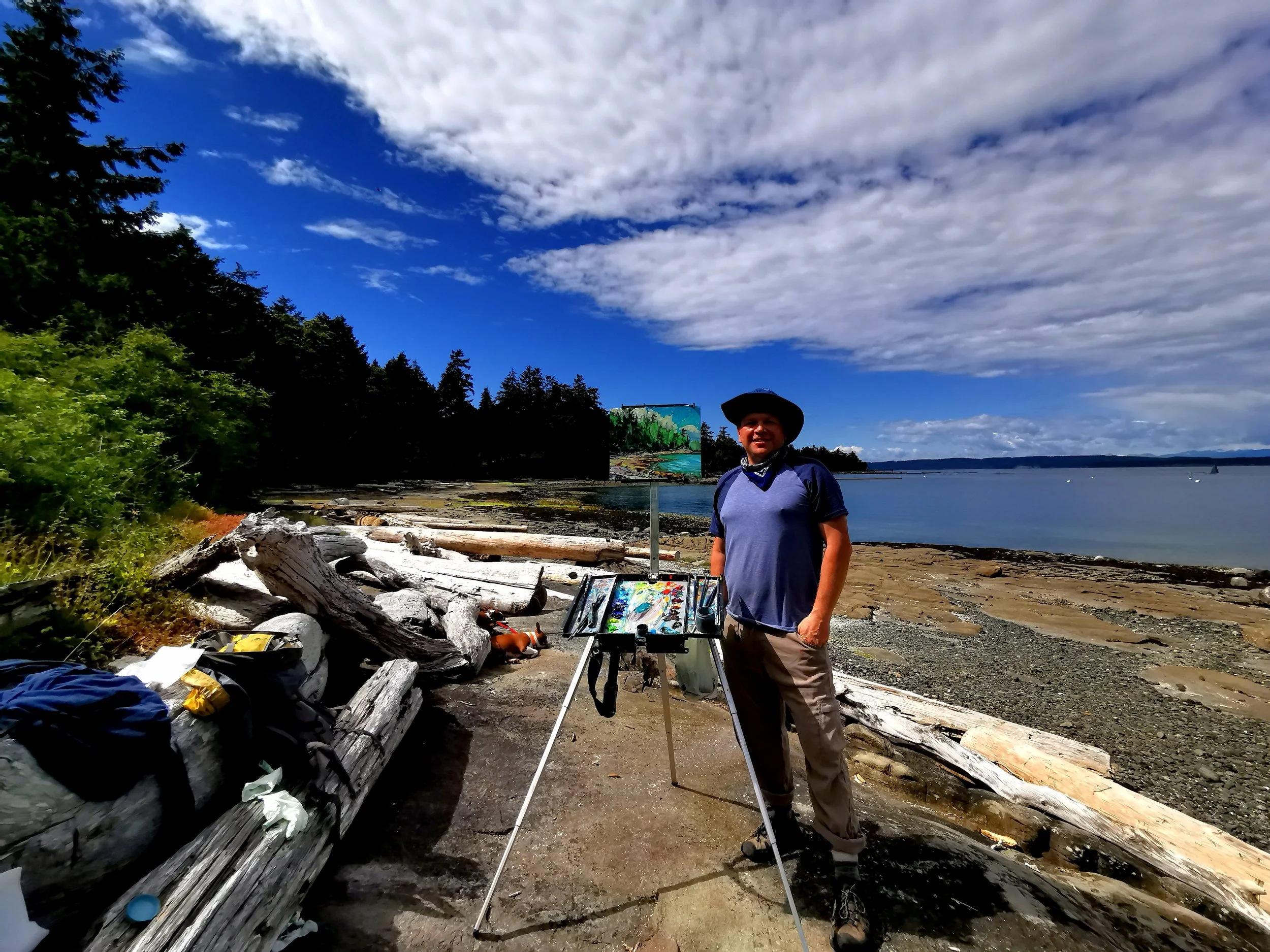 Artist Dominik Modlinski painting en plein air on a Vancouver Island beach during summer, capturing the coastal light and West Coast scenery.