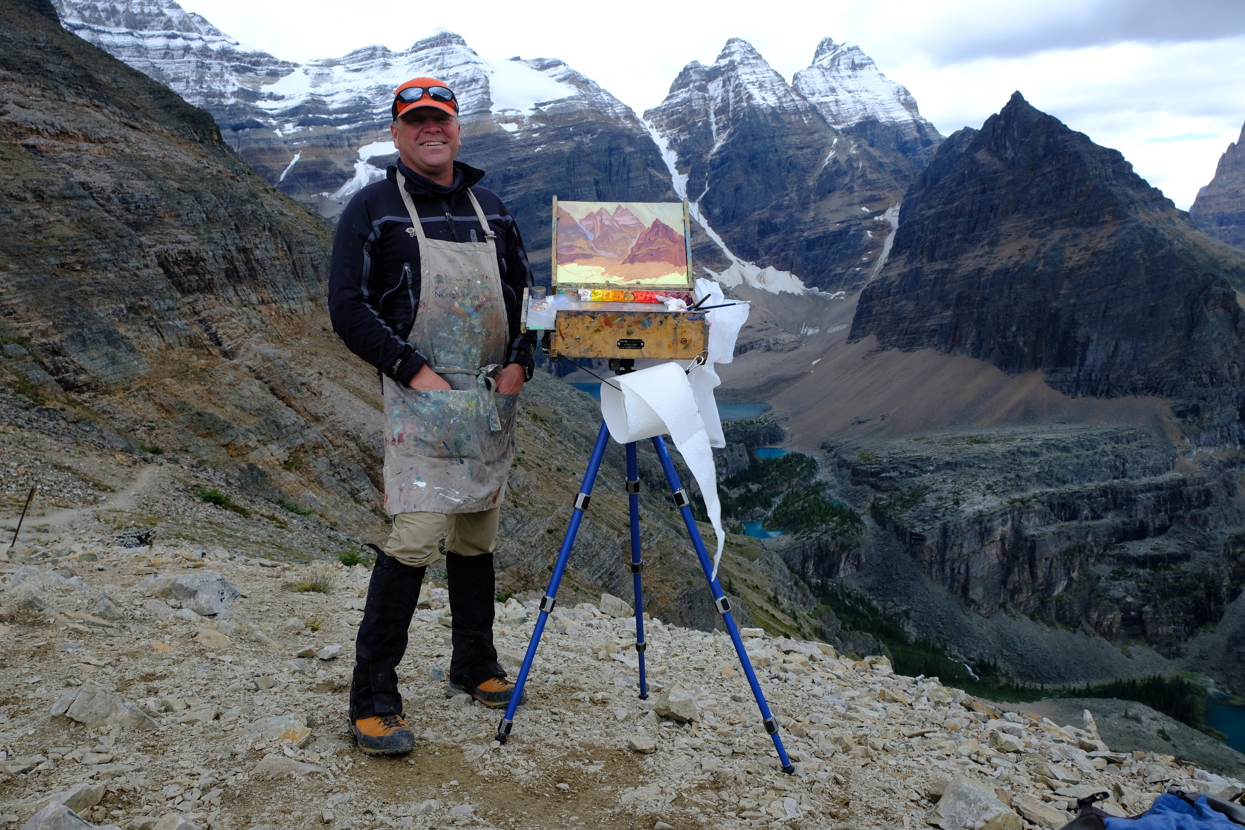 Artist painting en plein air above Lake O’Hara, surrounded by dramatic alpine peaks in the Canadian Rockies.